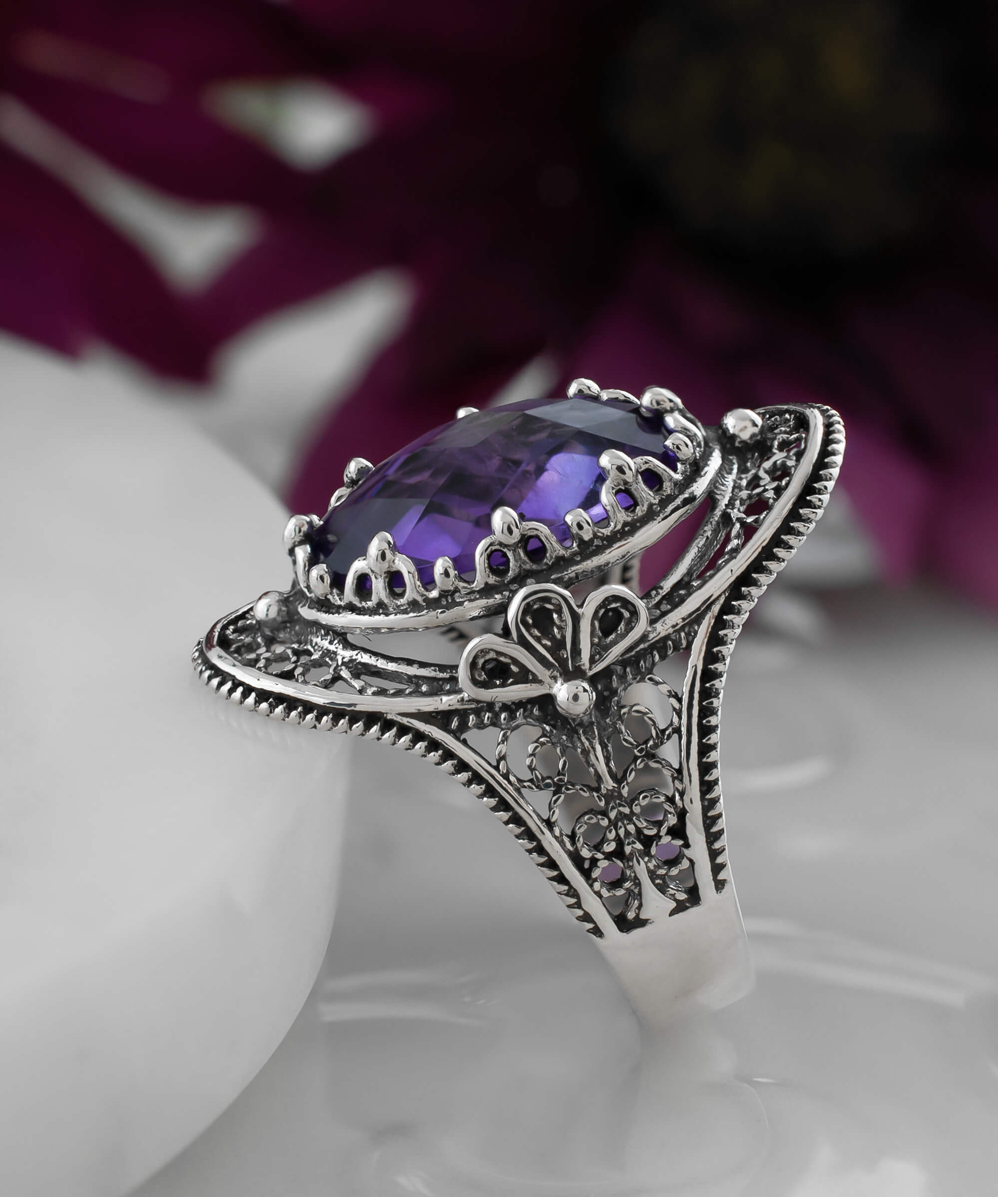 A stunning handmade silver statement ring featuring a double-sided oval cut amethyst gemstone in a delicate filigree design.