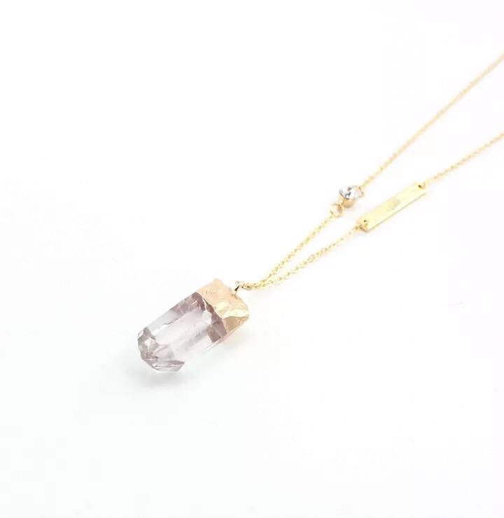 A beautifully handmade quartz pendant necklace with gold plated accents, showcasing a lengthy chain and sparkling details.