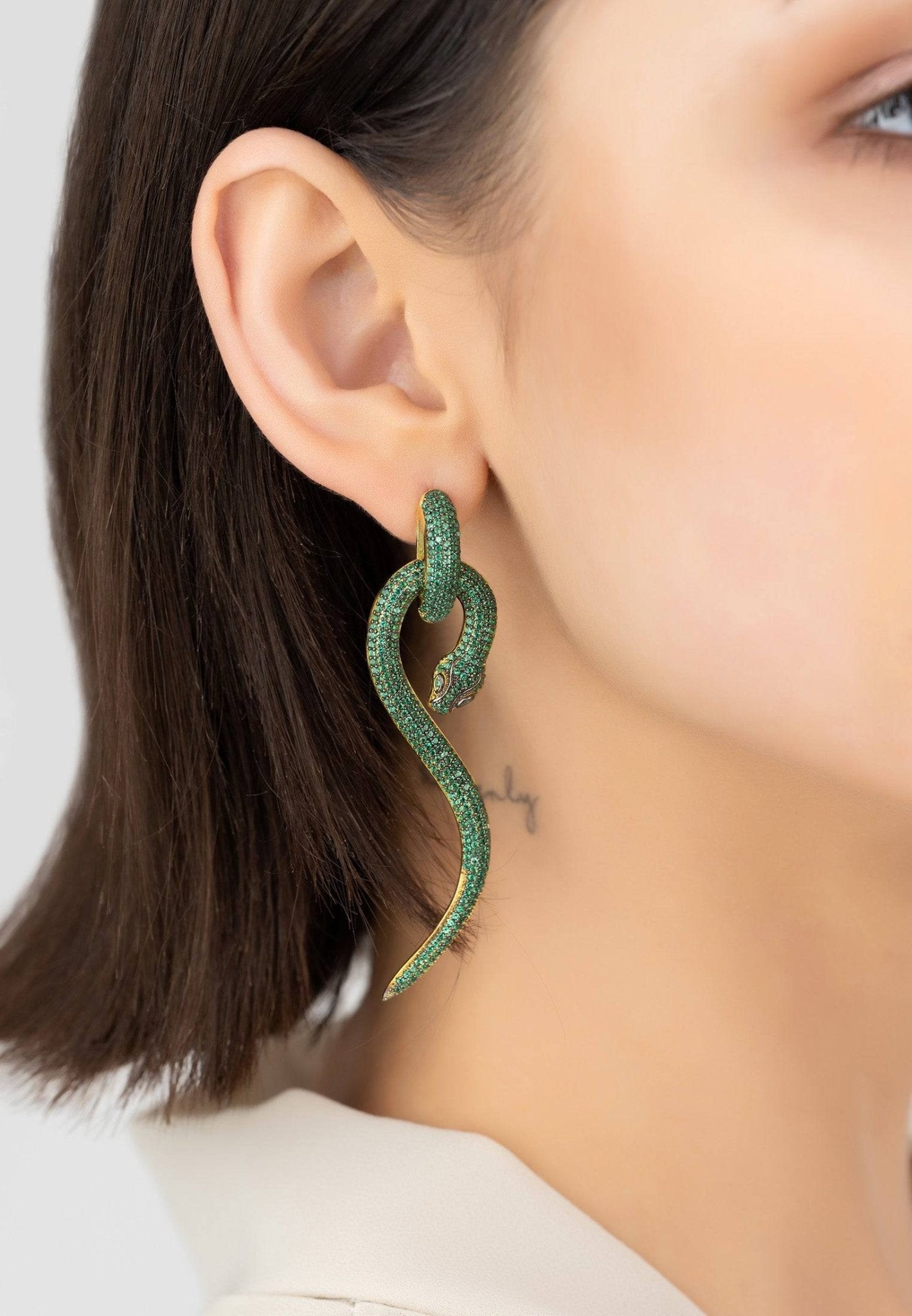 Anaconda snake drop earrings in gold with emerald cubic zirconia, showcasing a unique and elegant design.