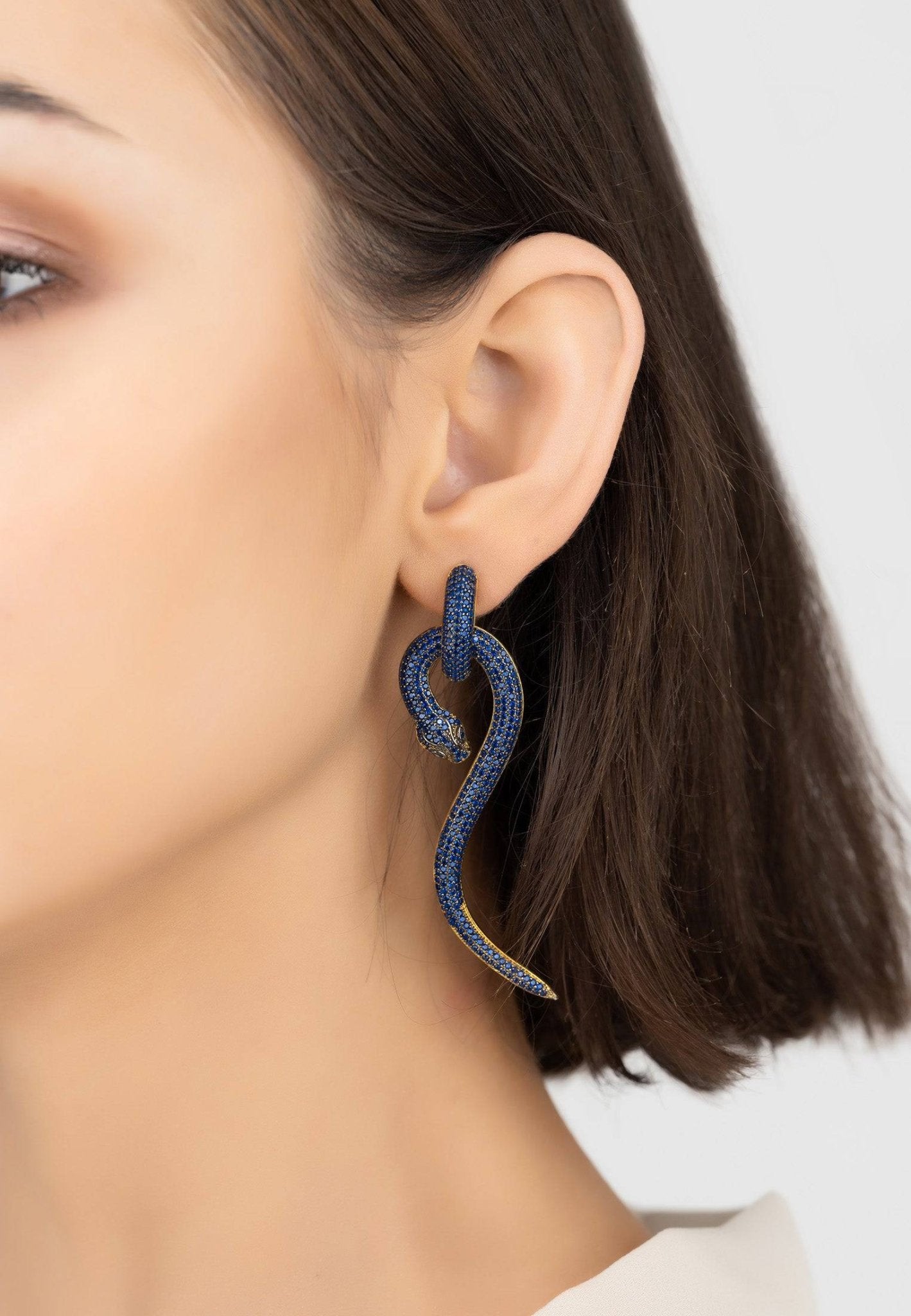 Anaconda snake drop earrings in gold with sapphire accents, showcasing intricate design and craftsmanship.