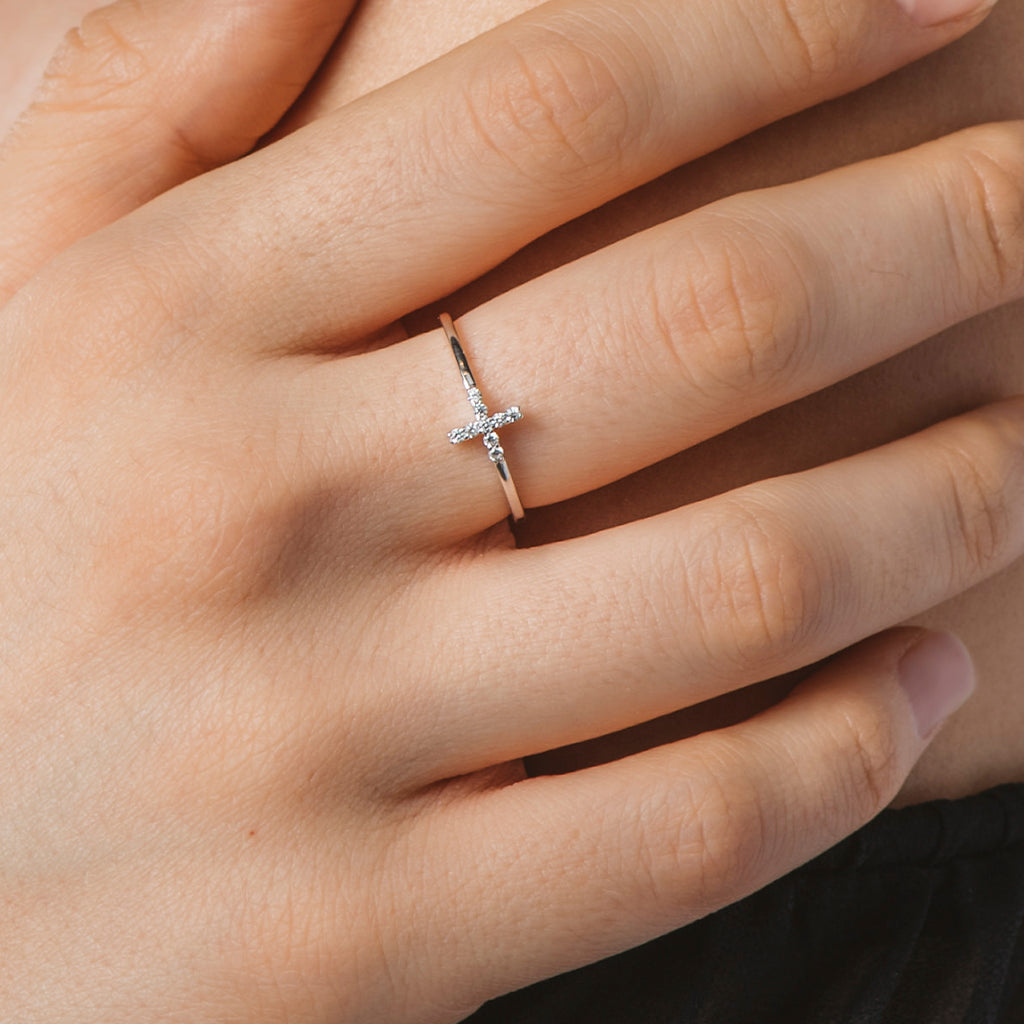 Anillo de plata con diseño de cruz y circonitas blancas brillantes, presentado en una elegante caja de regalo.