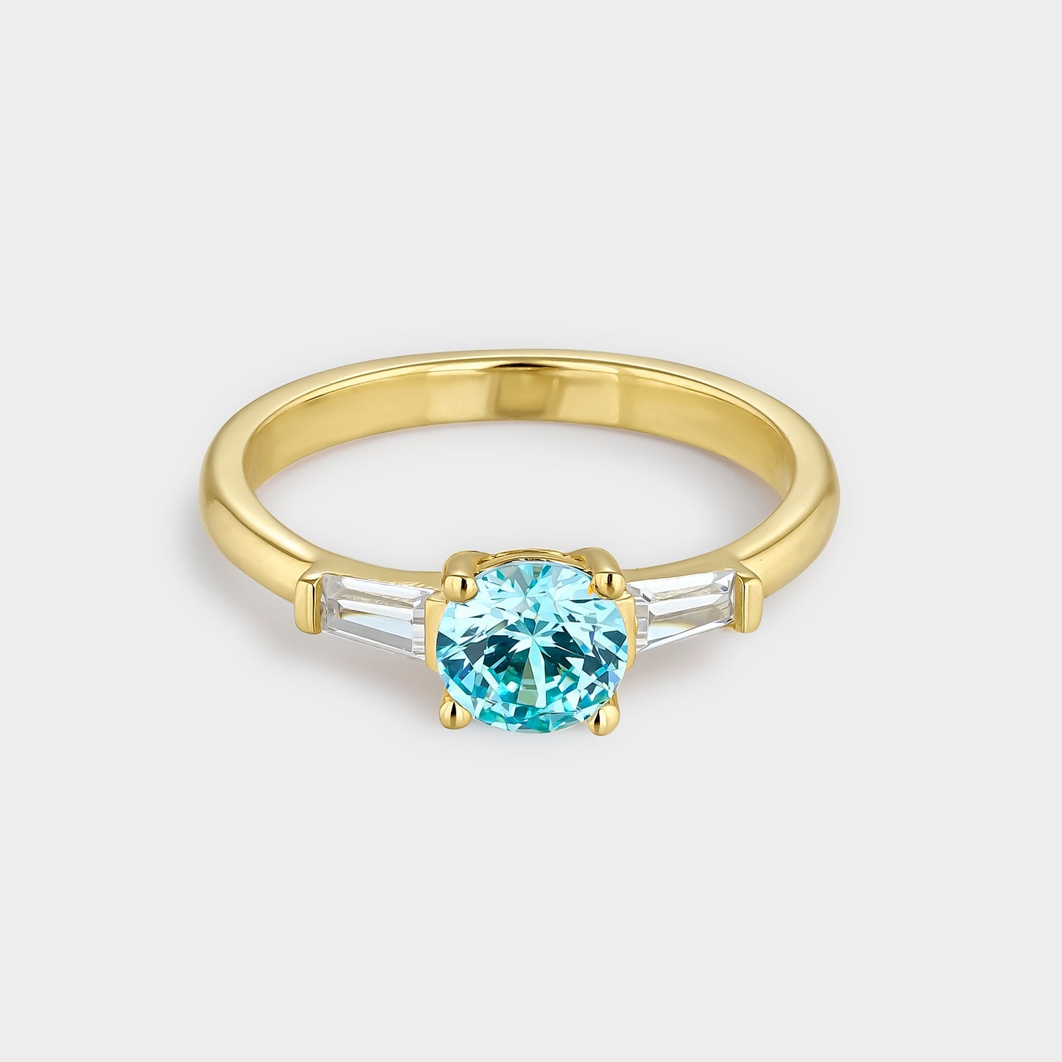 Anillo trío elegante con circonita azul aguamarina y circonitas blancas, fabricado en plata bañada en oro amarillo de 18K.