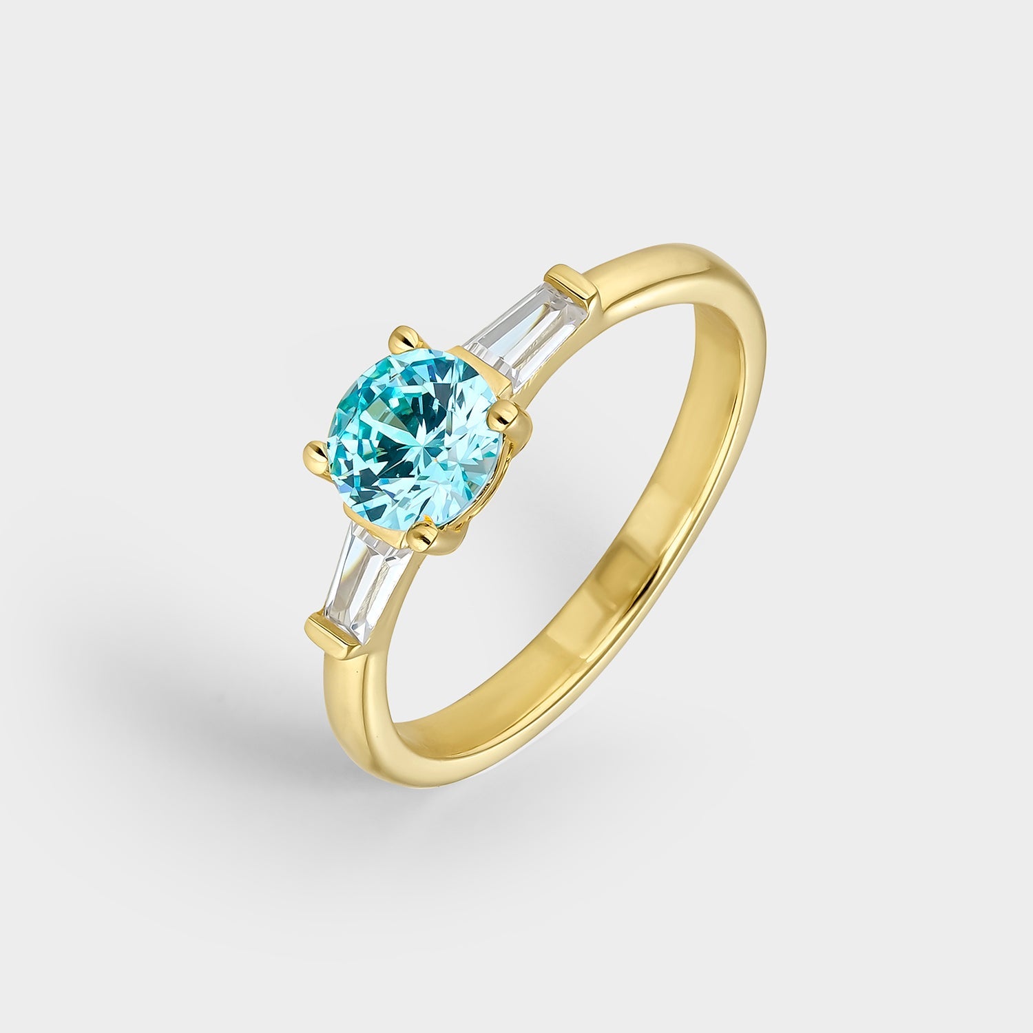 Anillo trío elegante con circonita azul aguamarina y circonitas blancas, fabricado en plata bañada en oro amarillo de 18K.