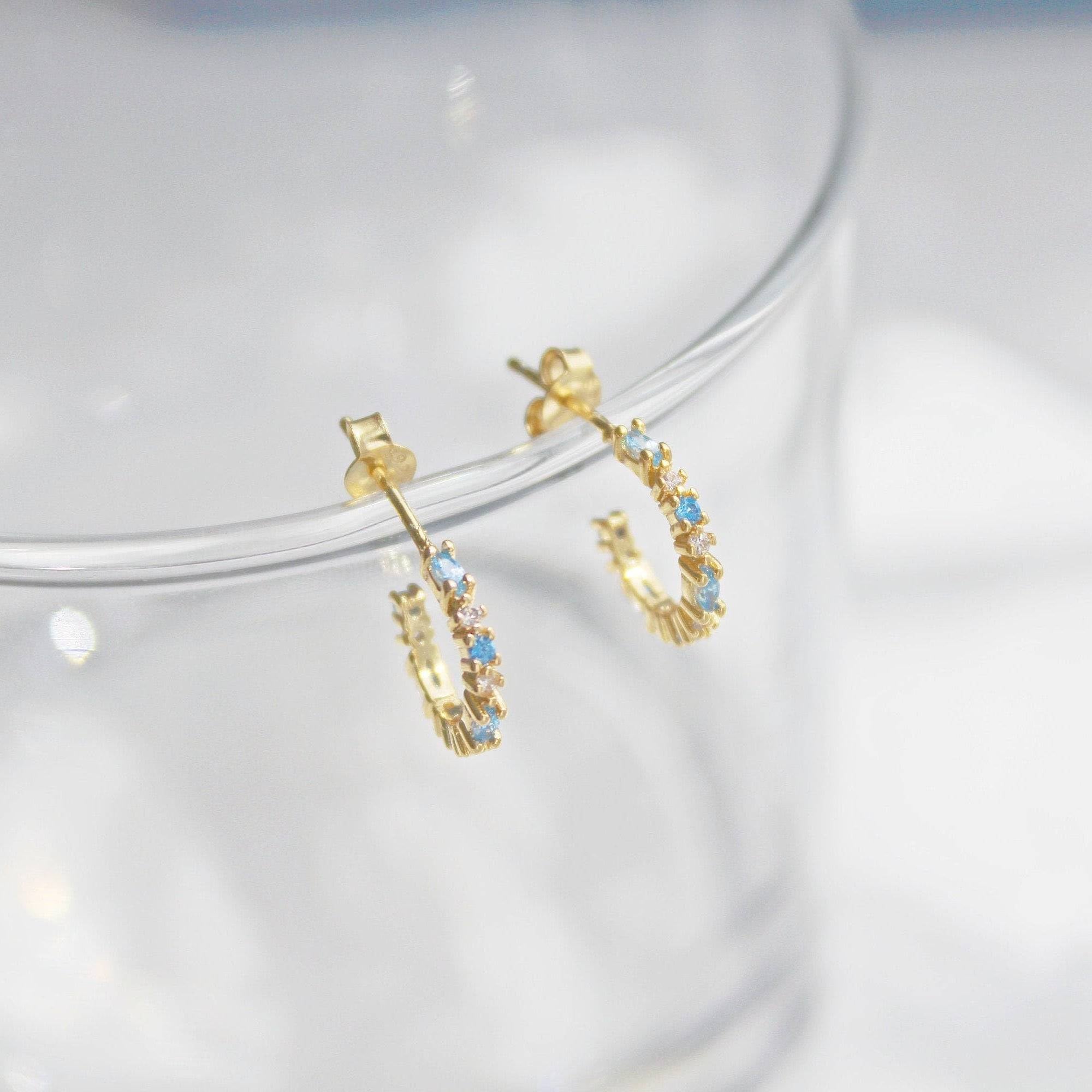 Aquamarine Mini Hoop Earrings featuring sterling silver and gold plating with sparkling blue crystals, elegantly displayed in a gift box.