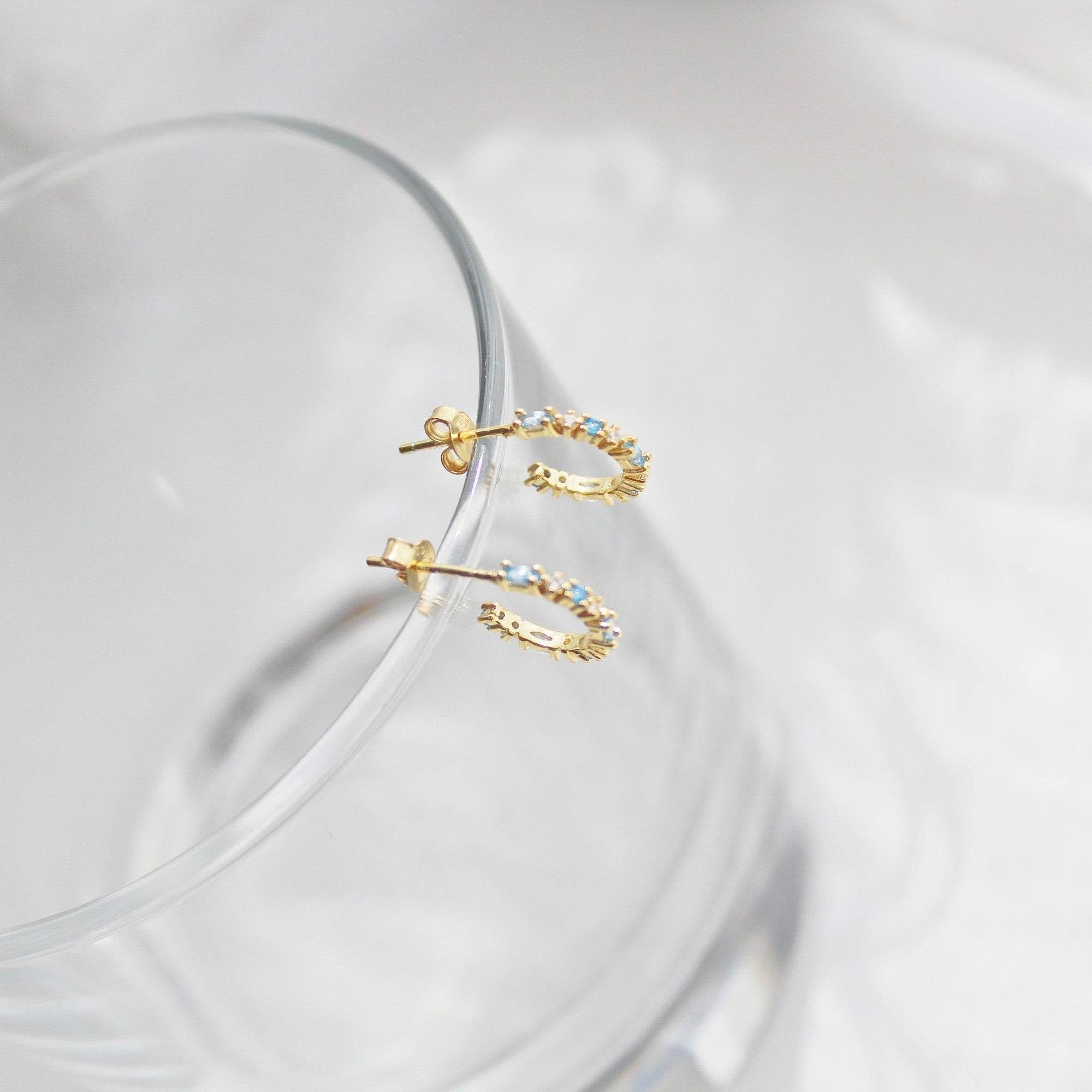 Aquamarine Mini Hoop Earrings featuring sterling silver and gold plating with sparkling blue crystals, elegantly displayed in a gift box.