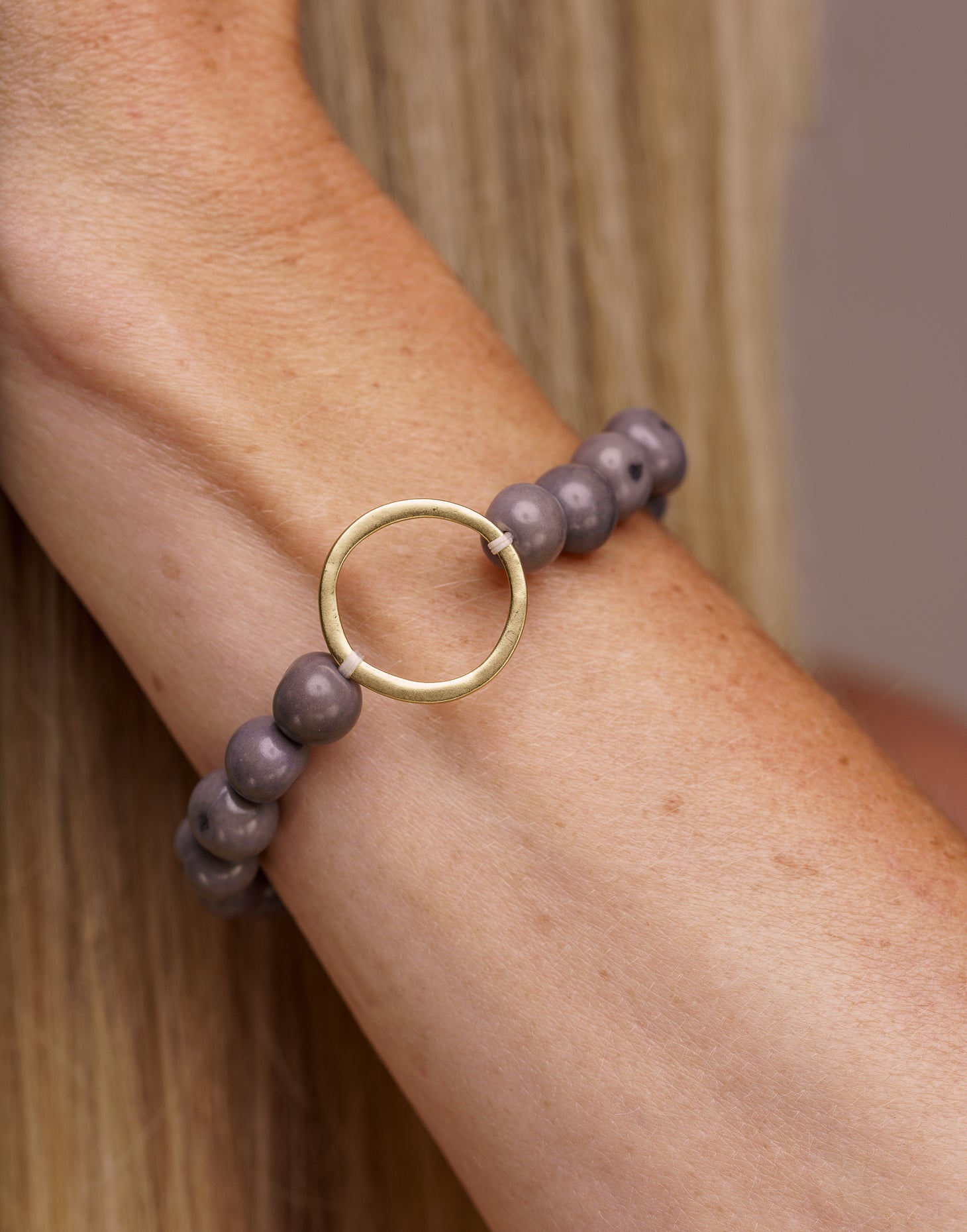 Argola Brass Acai Bracelet in grey featuring hand-drilled Acai seeds and a raw brass hoop detail, showcasing its unique organic design.