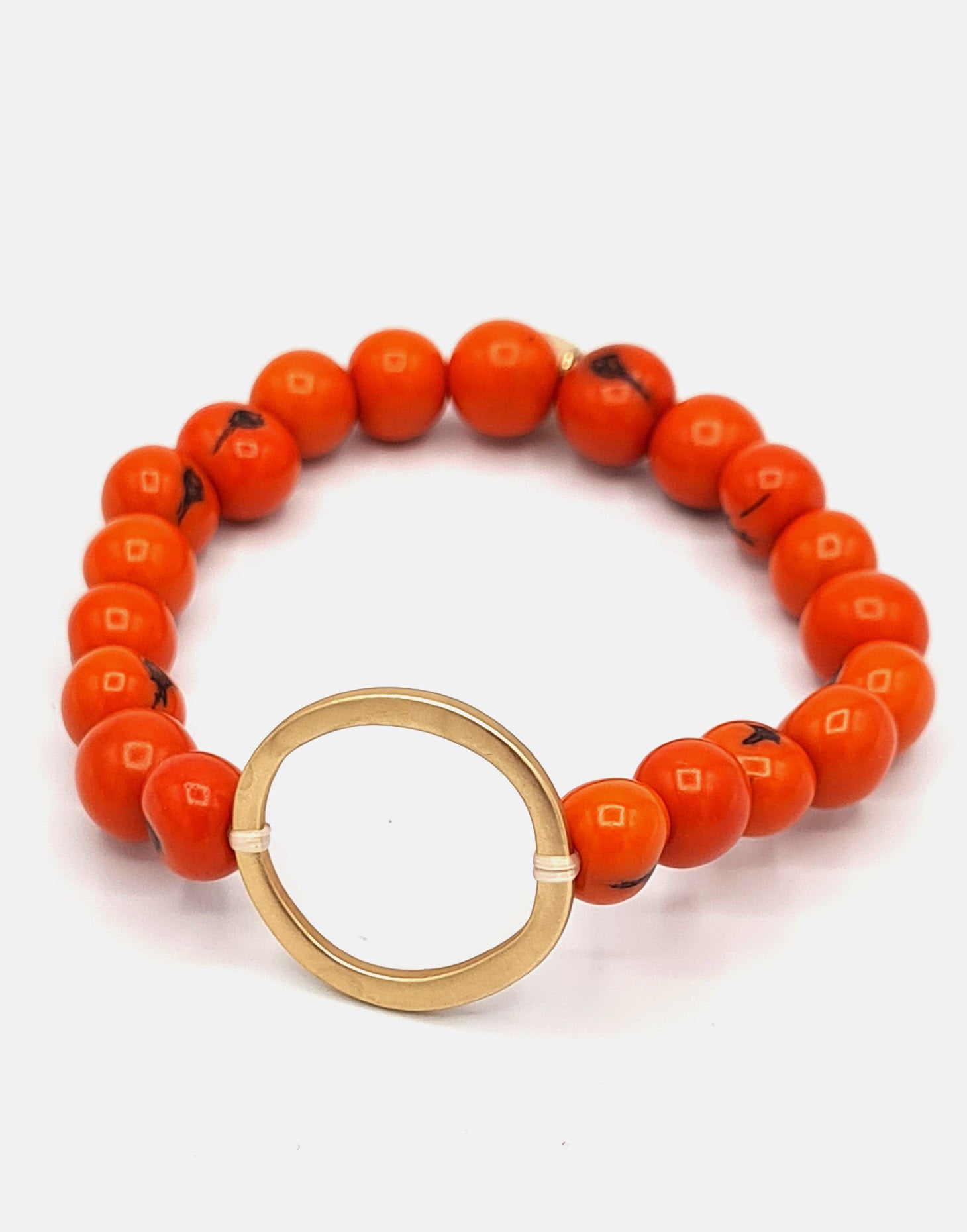 Argola Brass Acai Bracelet in vibrant orange featuring hand-drilled Acai seeds and a raw brass hoop detail.