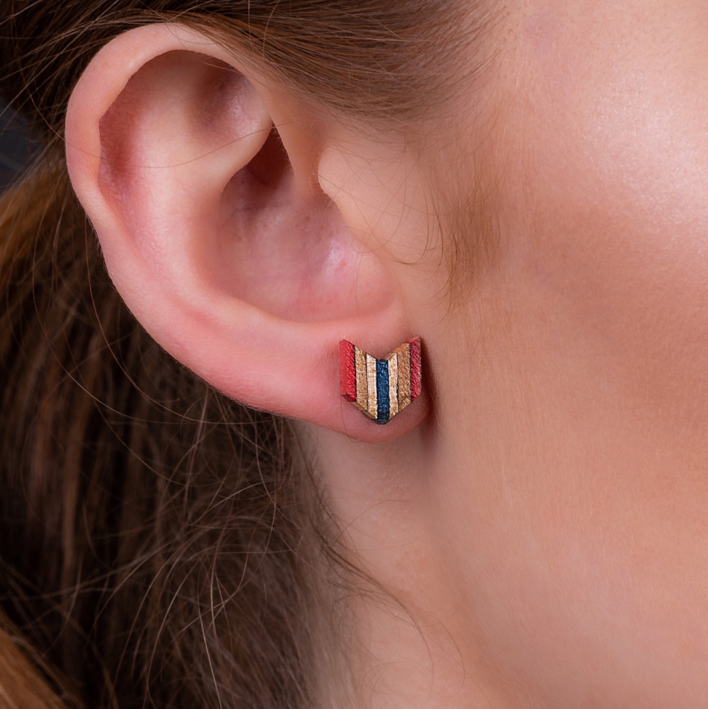 A pair of Arrow Colourful Recycled Skateboard Stud Earrings showcasing vibrant colors and unique patterns from upcycled skateboard materials.