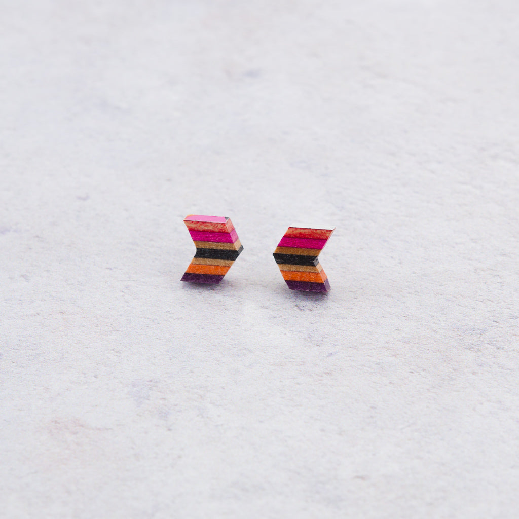 A pair of Arrow Colourful Recycled Skateboard Stud Earrings showcasing vibrant colors and unique patterns from upcycled skateboard materials.