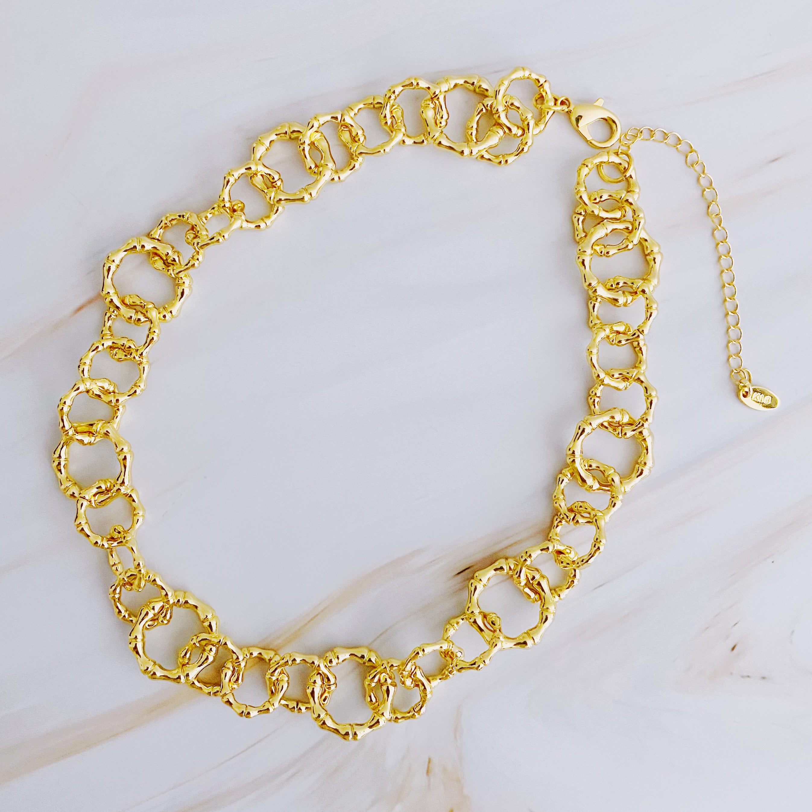 Artfully Linked Chain Necklace featuring varying link sizes and a polished gold finish, elegantly displayed against a soft background.