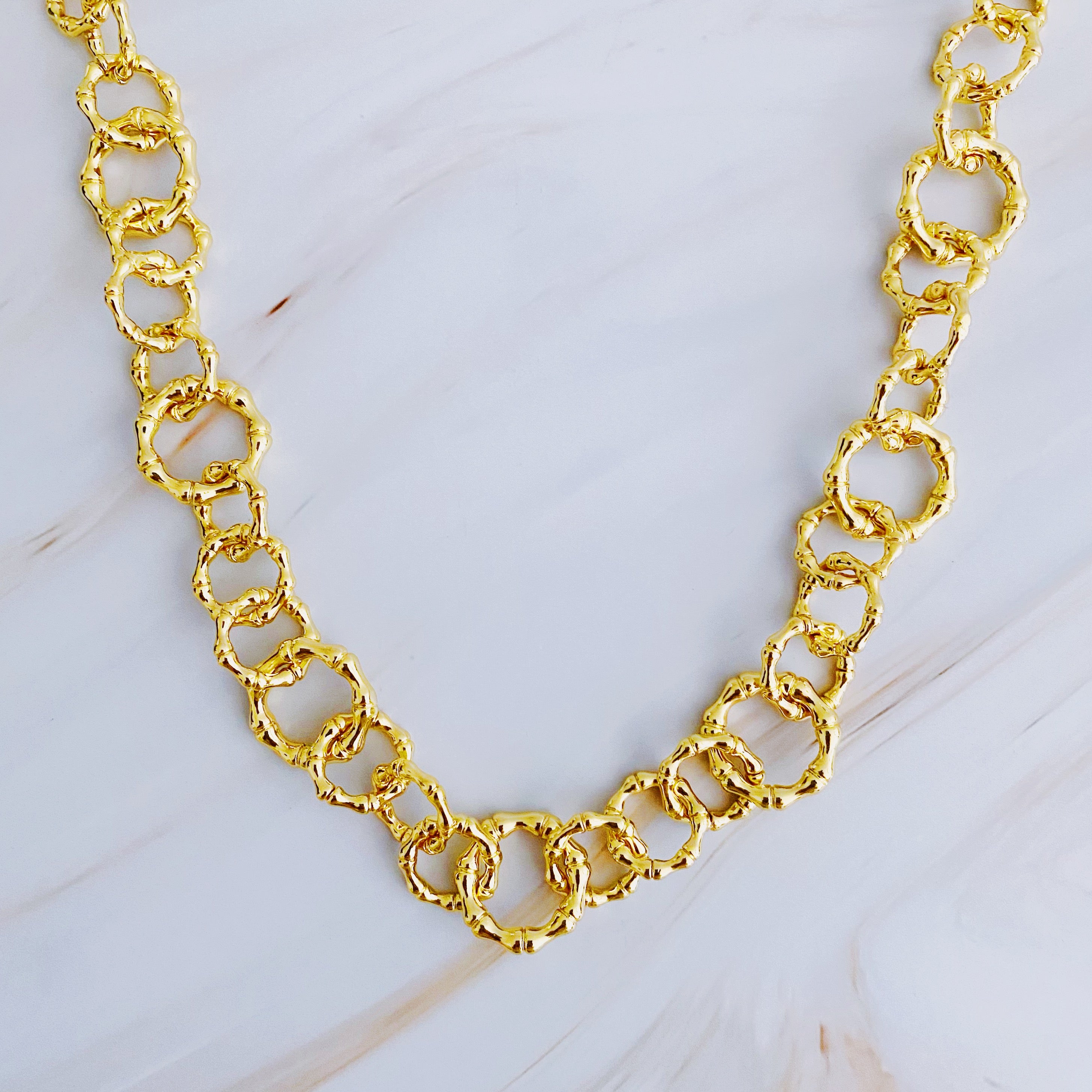 Artfully Linked Chain Necklace featuring varying link sizes and a polished gold finish, elegantly displayed against a soft background.