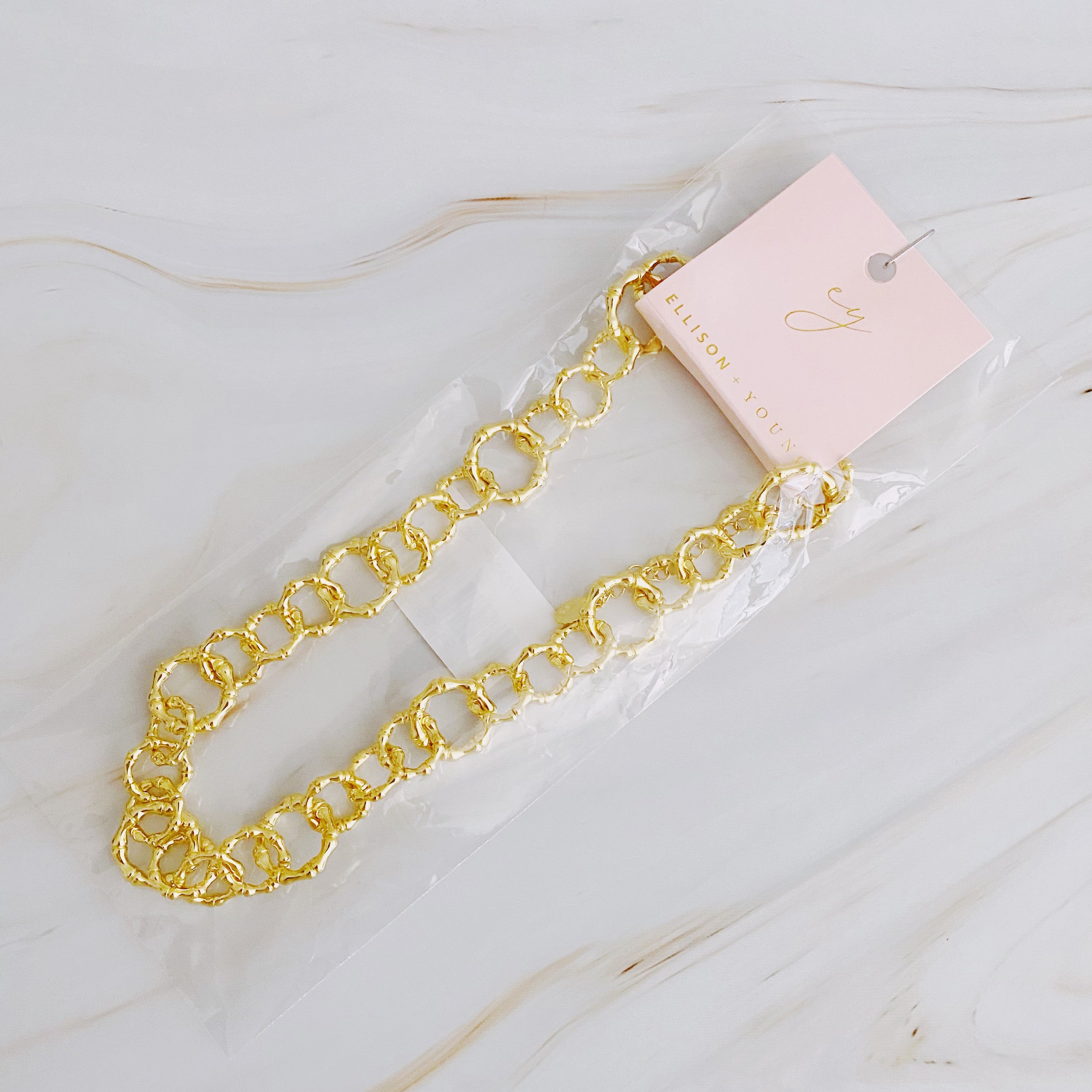 Artfully Linked Chain Necklace featuring varying link sizes and a polished gold finish, elegantly displayed against a soft background.