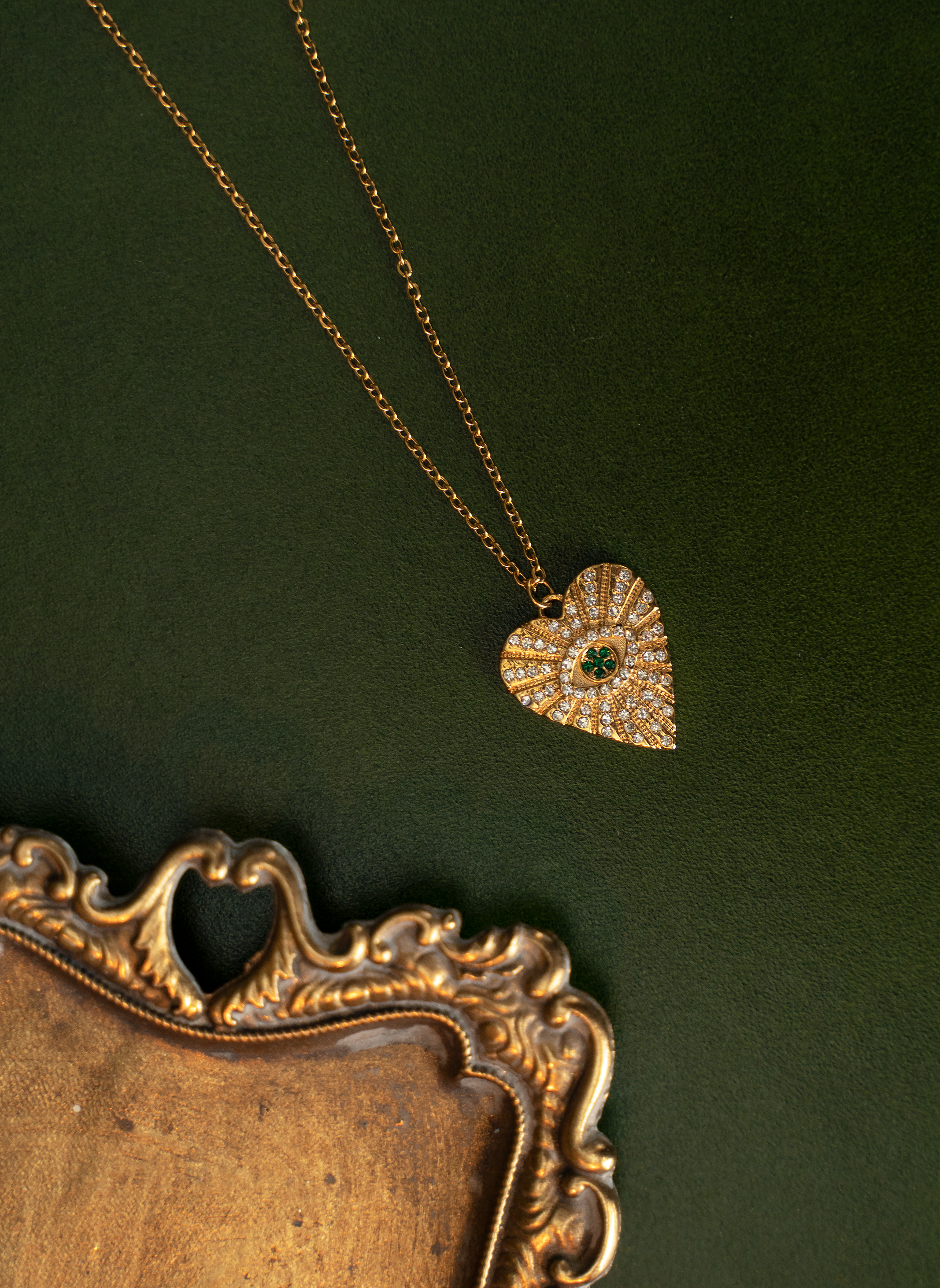 ASHA Heart Necklace featuring sparkling white and emerald crystals on a gold plated heart pendant with a cable chain.