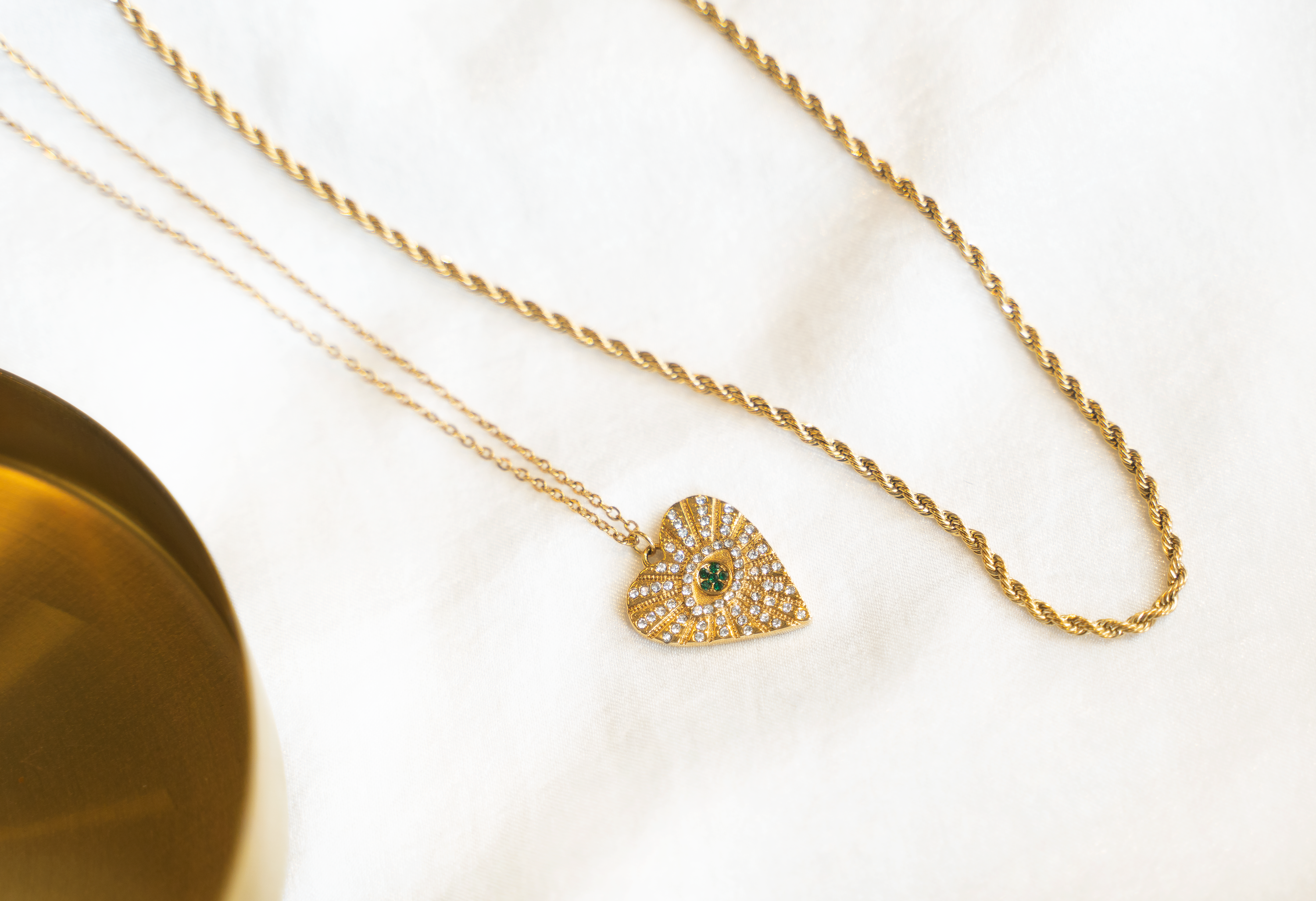 ASHA Heart Necklace featuring sparkling white and emerald crystals on a gold plated heart pendant with a cable chain.