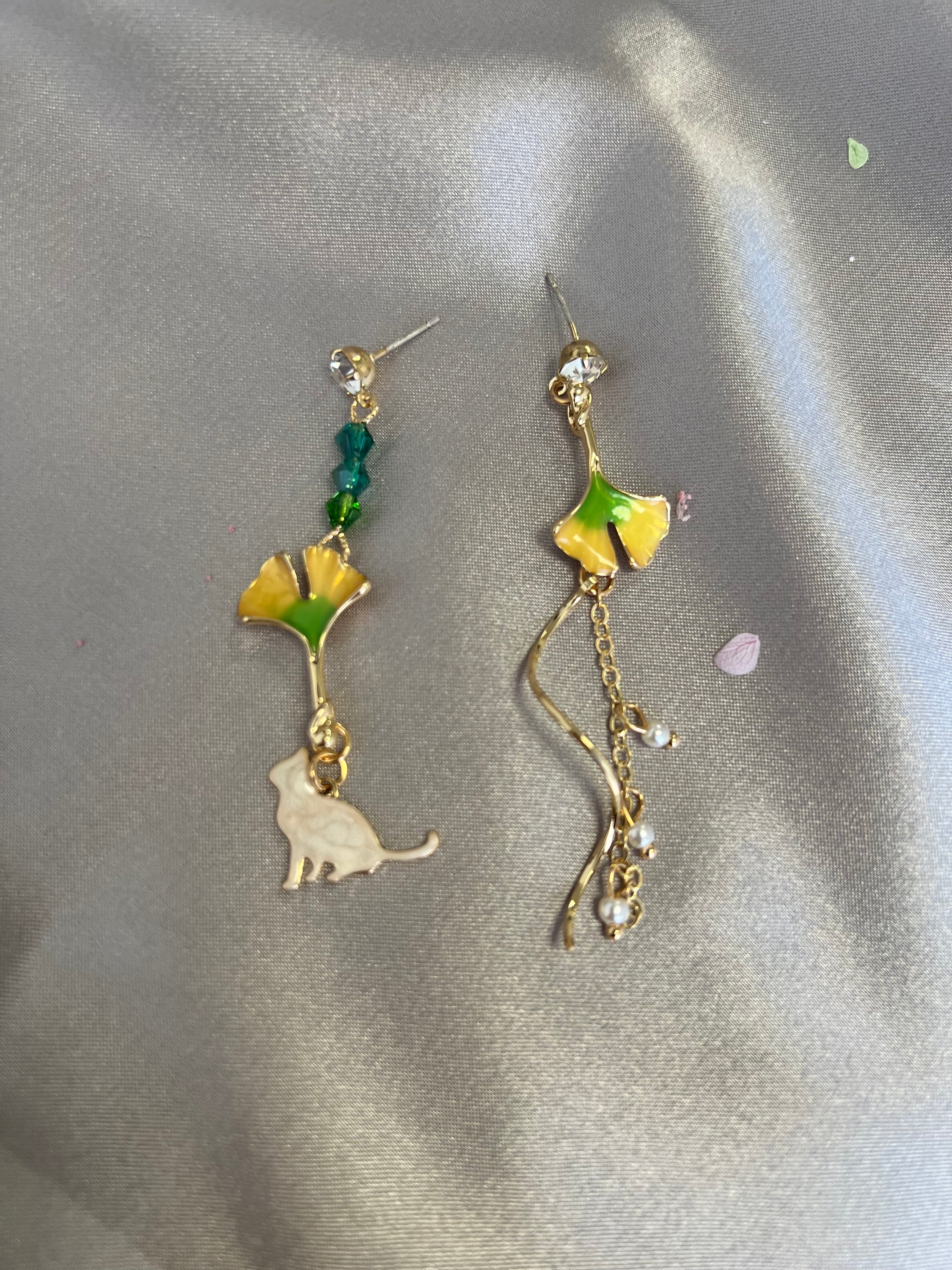 Asymmetric earrings featuring a ginkgo leaf design with a cat motif, embellished with rhinestones and artificial pearls.