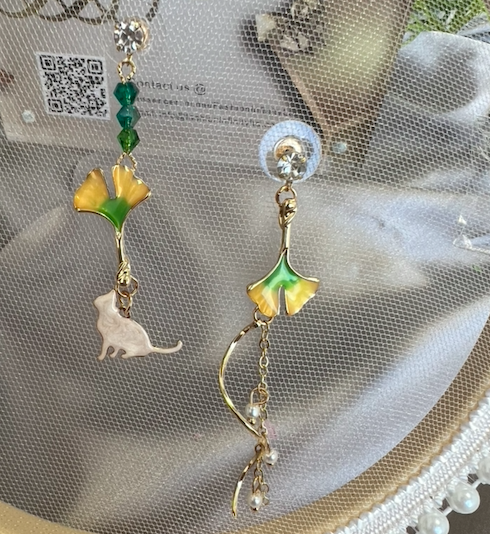 Asymmetric earrings featuring a ginkgo leaf design with a cat motif, embellished with rhinestones and artificial pearls.