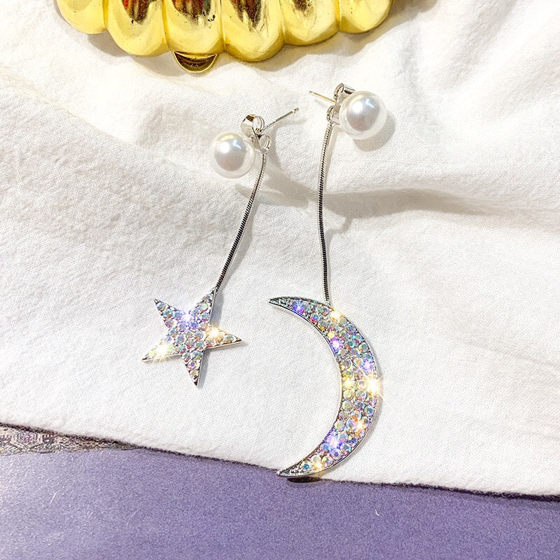 Asymmetric earrings featuring moon and star designs, adorned with pearls and rhinestones, showcasing a celestial theme.