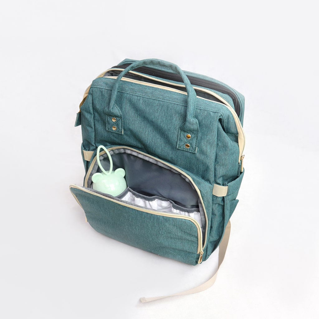 A stylish Baby Crib Backpack showcasing its multi-functional design, featuring a diaper compartment, insulated bottle pocket, and crib setup.