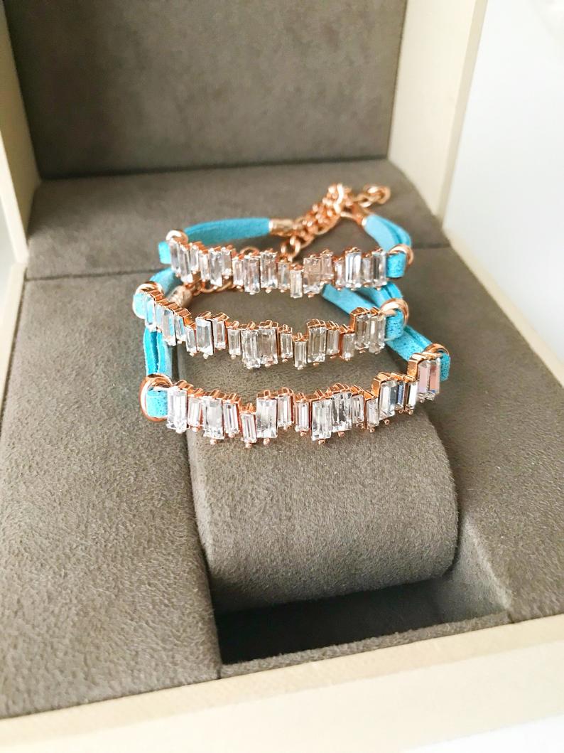 A stylish Baguette Bracelet featuring cubic zirconia stones set in a turquoise leather strap, showcasing a modern and elegant design.