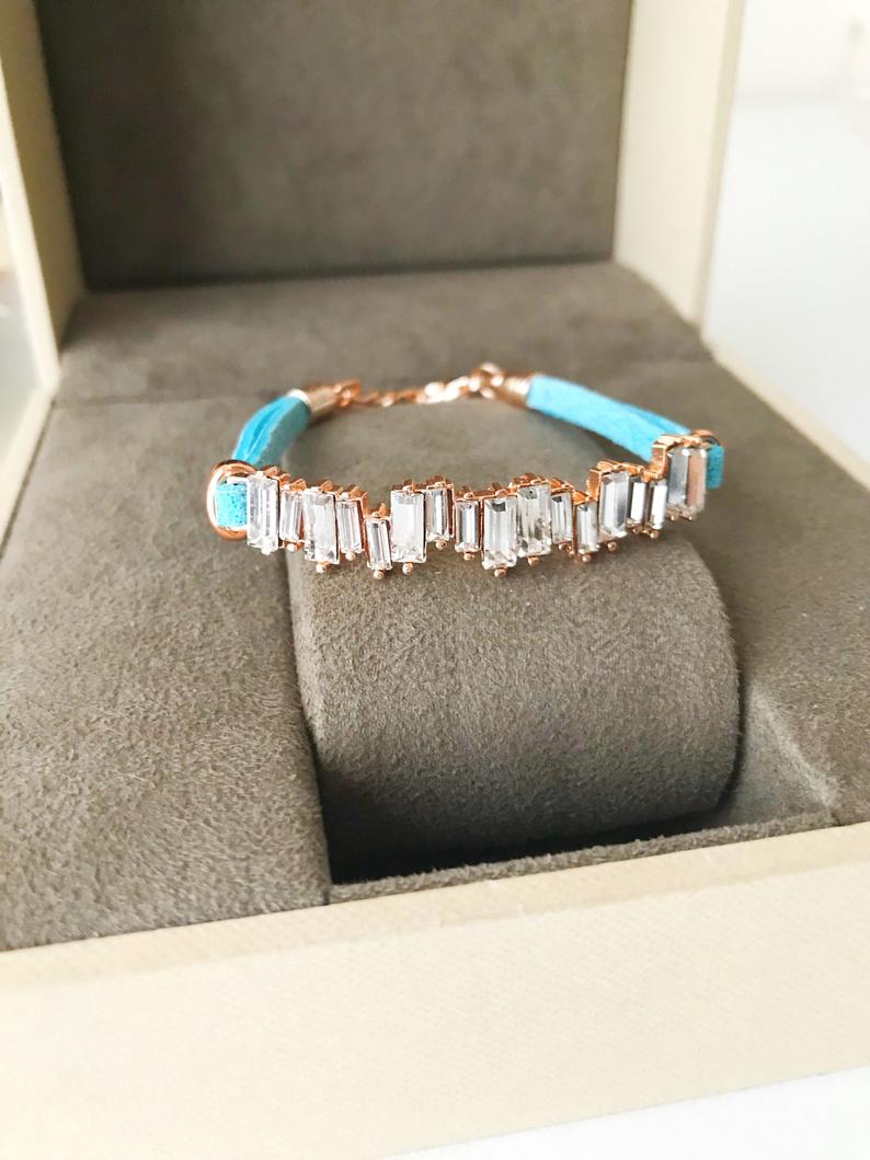 A stylish Baguette Bracelet featuring cubic zirconia stones set in a turquoise leather strap, showcasing a modern and elegant design.