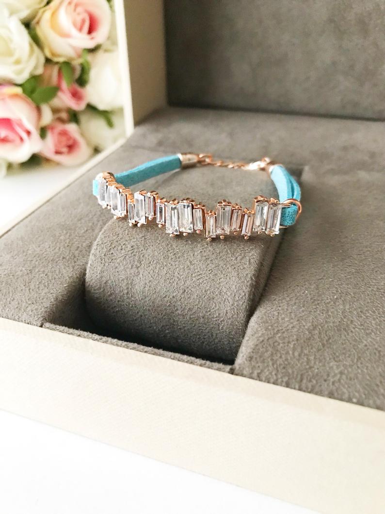 A stylish Baguette Bracelet featuring cubic zirconia stones set in a turquoise leather strap, showcasing a modern and elegant design.