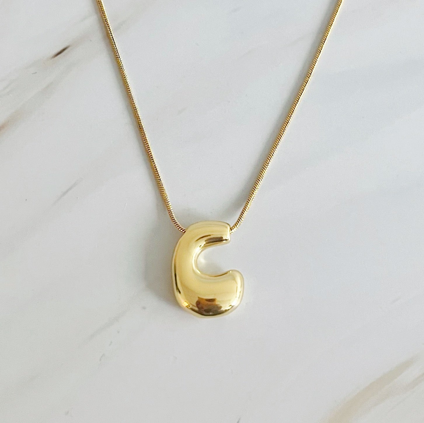 A stylish Balloon Letter Initial Necklace featuring a gold plated initial pendant on a delicate chain.