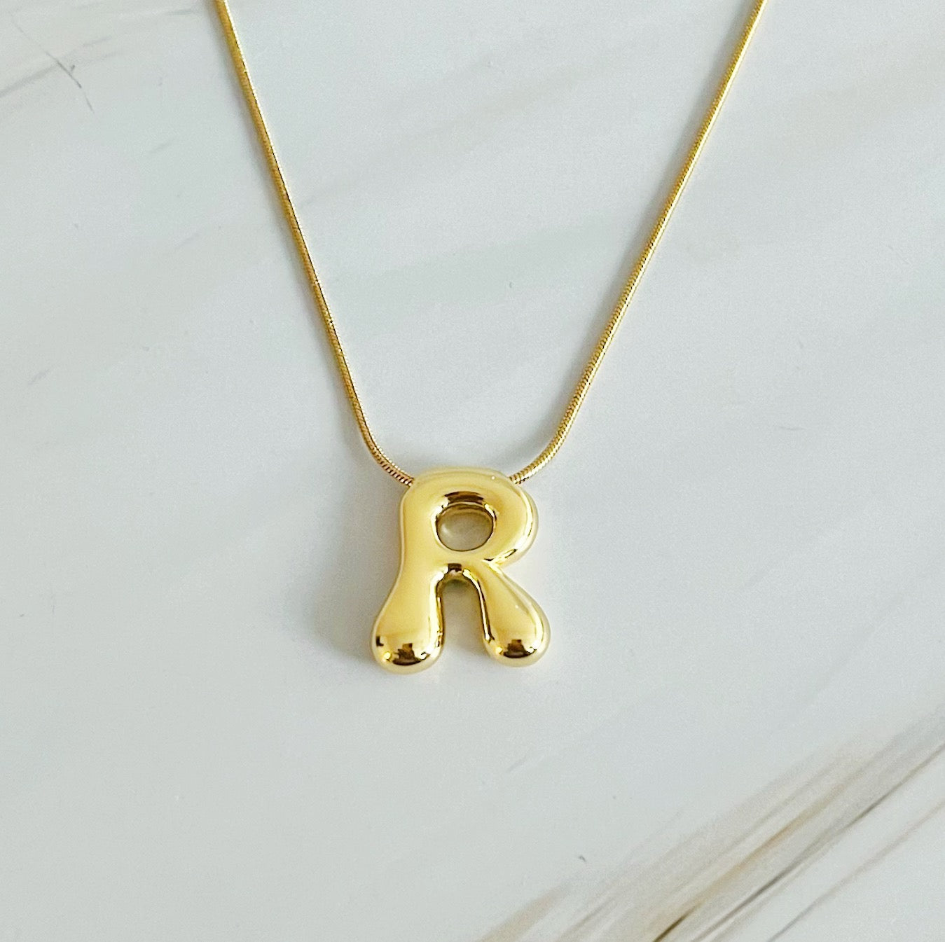 A stylish Balloon Letter Initial Necklace featuring a gold plated initial pendant on a delicate chain.