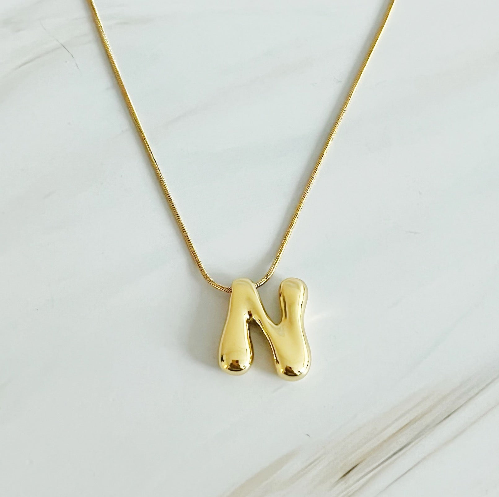 A stylish Balloon Letter Initial Necklace featuring a gold plated initial pendant on a delicate chain.