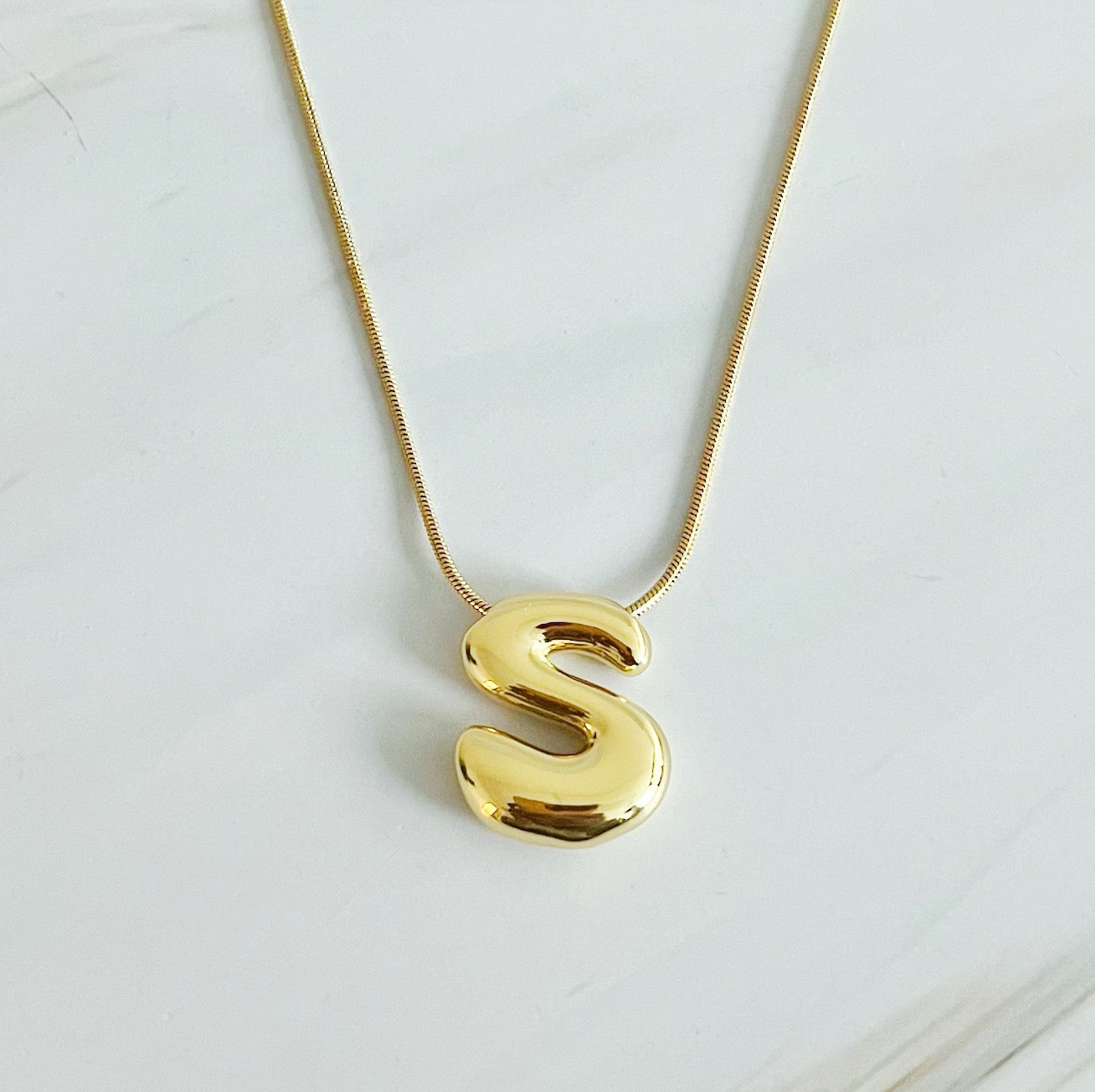 A stylish Balloon Letter Initial Necklace featuring a gold plated initial pendant on a delicate chain.