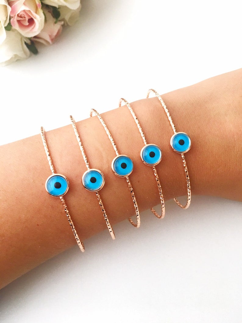 Handmade blue evil eye bangle bracelet with gold accents, featuring an adjustable design and multiple style options.