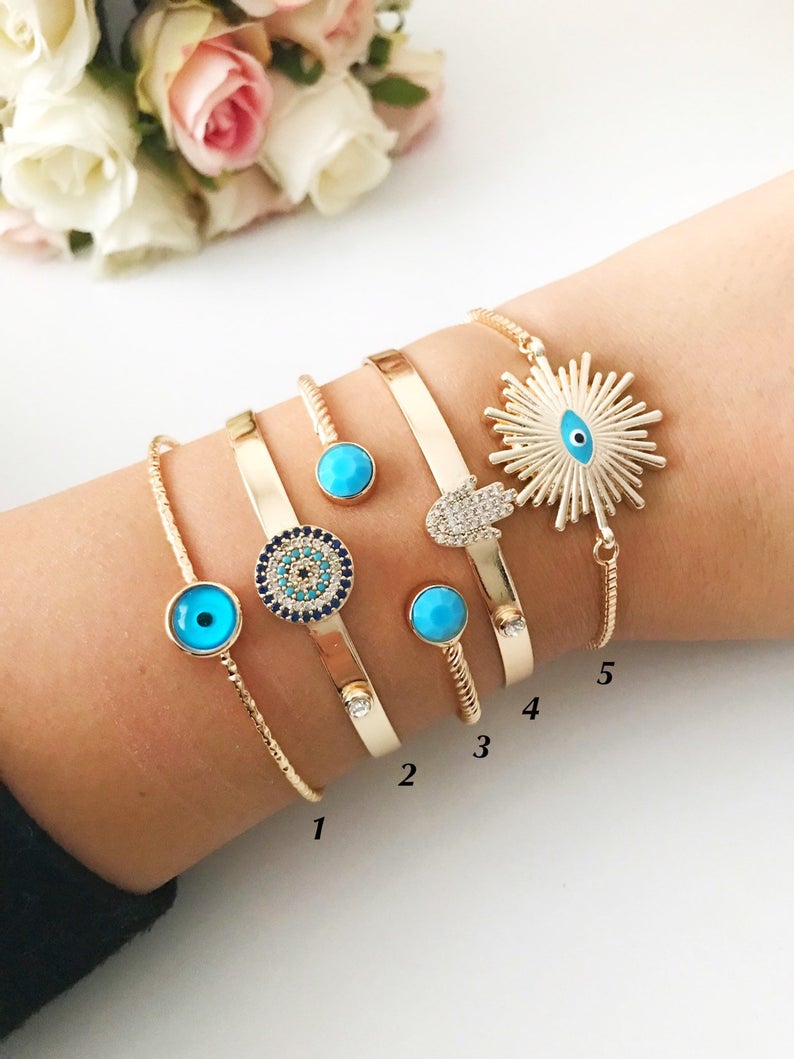 Handmade blue evil eye bangle bracelet with gold accents, featuring an adjustable design and multiple style options.