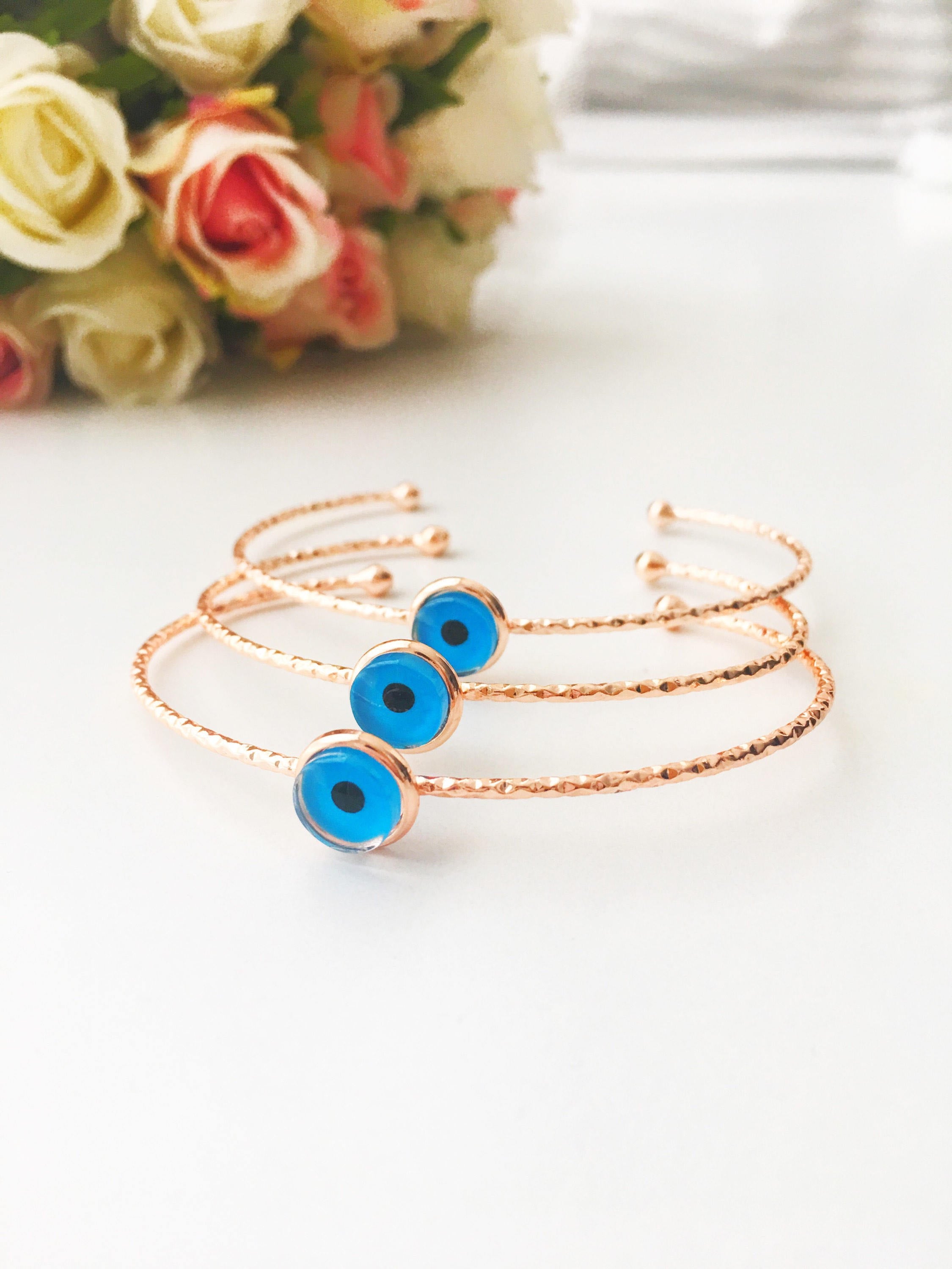 Bangle Evil Eye Bracelet featuring a movable blue evil eye charm on a rose gold stainless steel bangle, showcasing its elegant design.