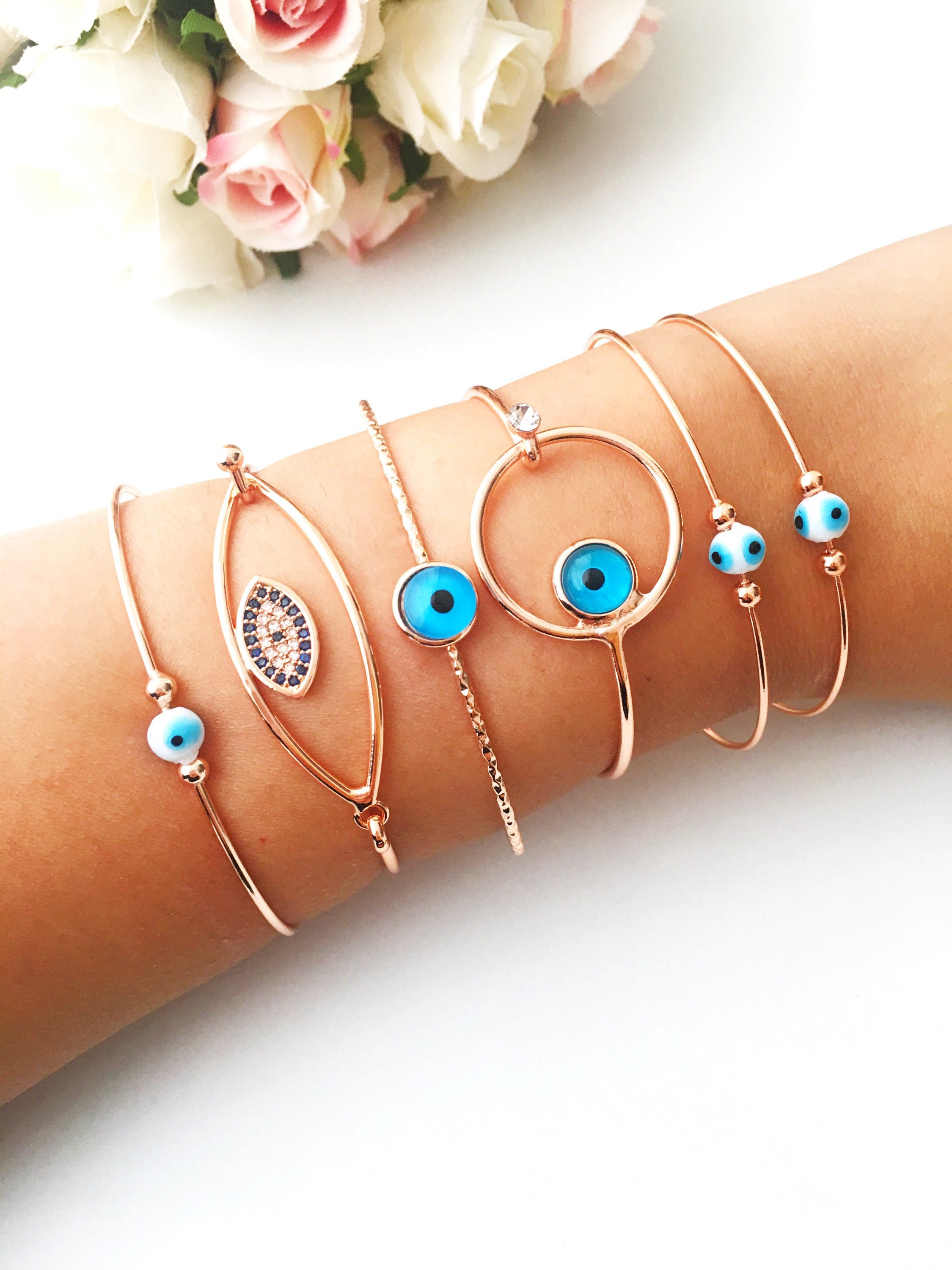 Bangle Evil Eye Bracelet featuring a movable blue evil eye charm on a rose gold stainless steel bangle, showcasing its elegant design.