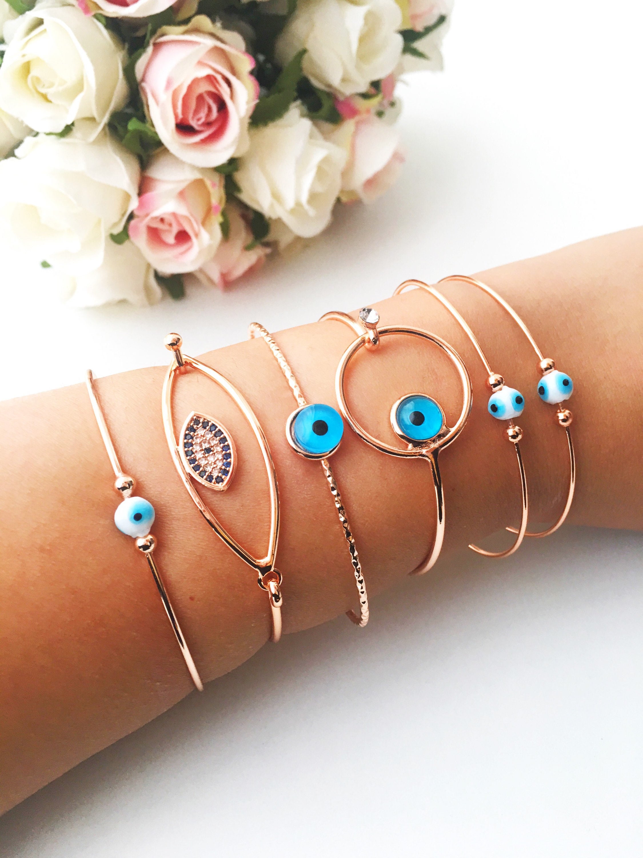 Bangle Evil Eye Bracelet featuring a movable blue evil eye charm on a rose gold stainless steel bangle, showcasing its elegant design.