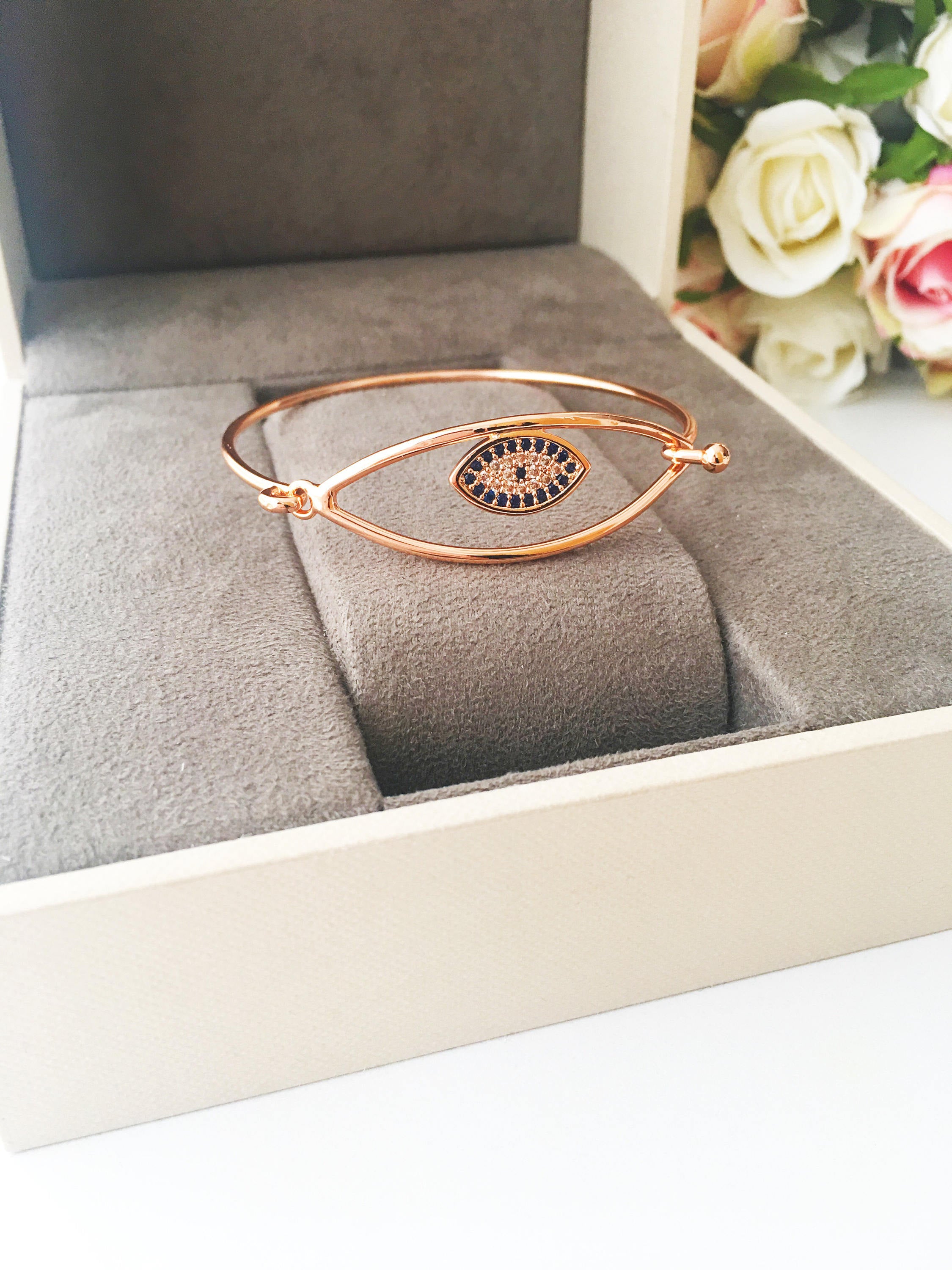 Bangle Evil Eye Bracelet featuring a movable blue evil eye charm on a rose gold stainless steel bangle, showcasing its elegant design.