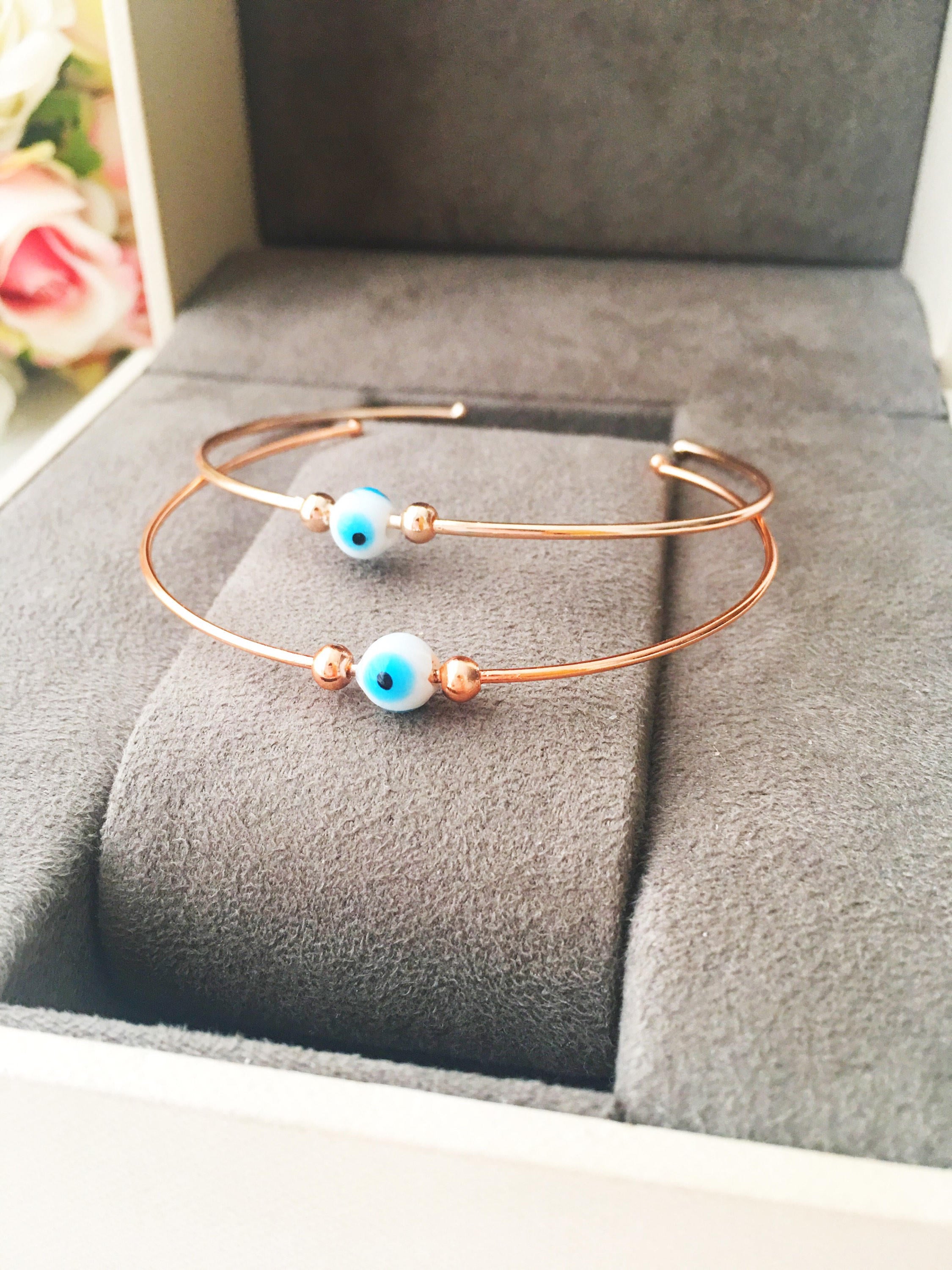 Bangle Evil Eye Bracelet featuring a movable blue evil eye charm on a rose gold stainless steel bangle, showcasing its elegant design.