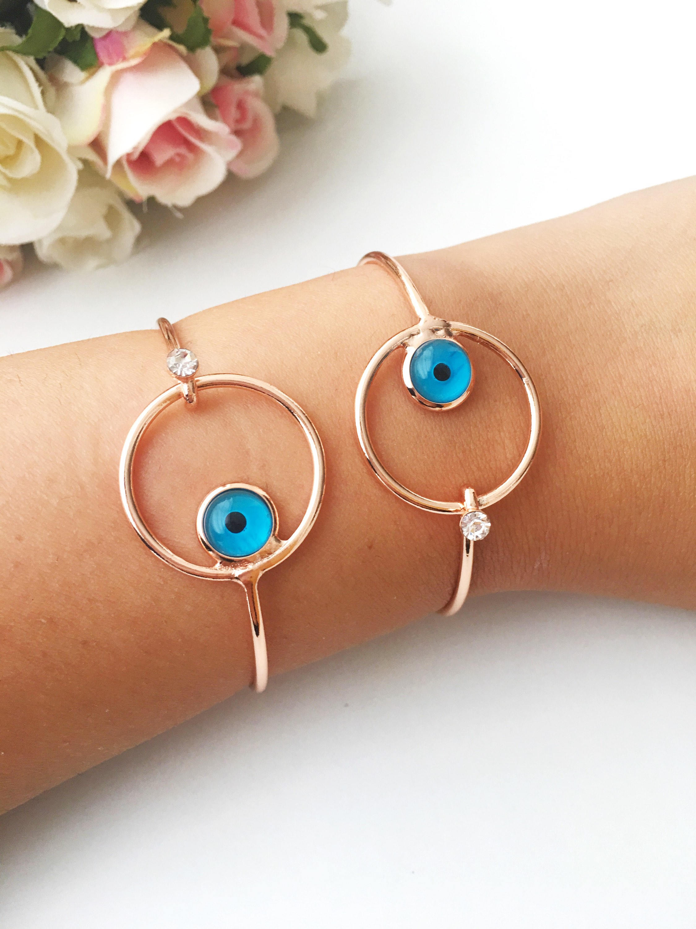 Bangle Evil Eye Bracelet featuring a movable blue evil eye charm on a rose gold stainless steel bangle, showcasing its elegant design.