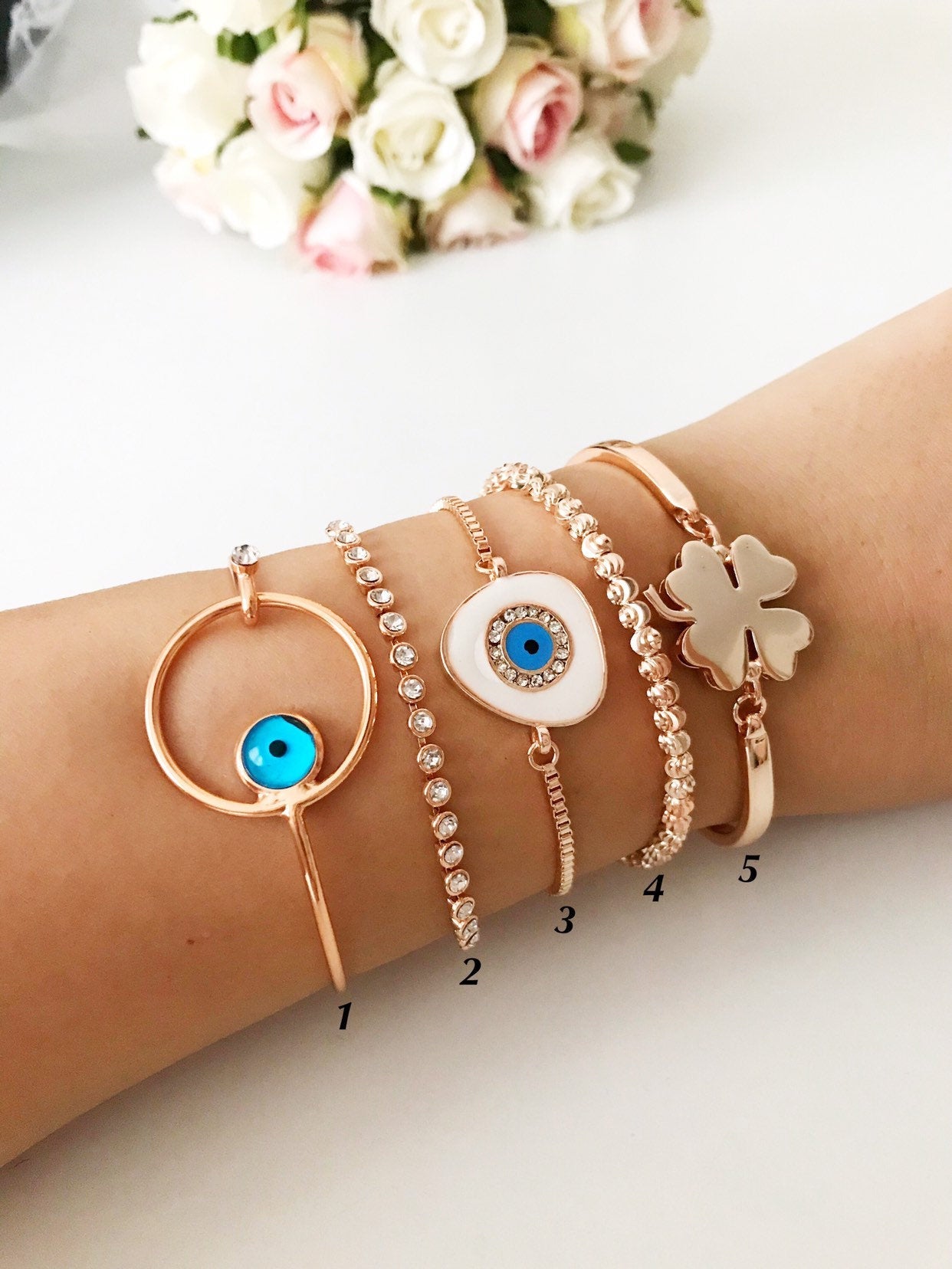 A beautiful rose gold bangle bracelet featuring a movable evil eye charm, showcasing intricate handmade craftsmanship.