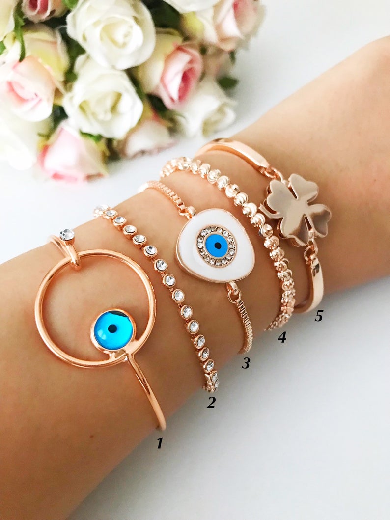 A beautiful rose gold bangle bracelet featuring a movable evil eye charm, showcasing intricate handmade craftsmanship.