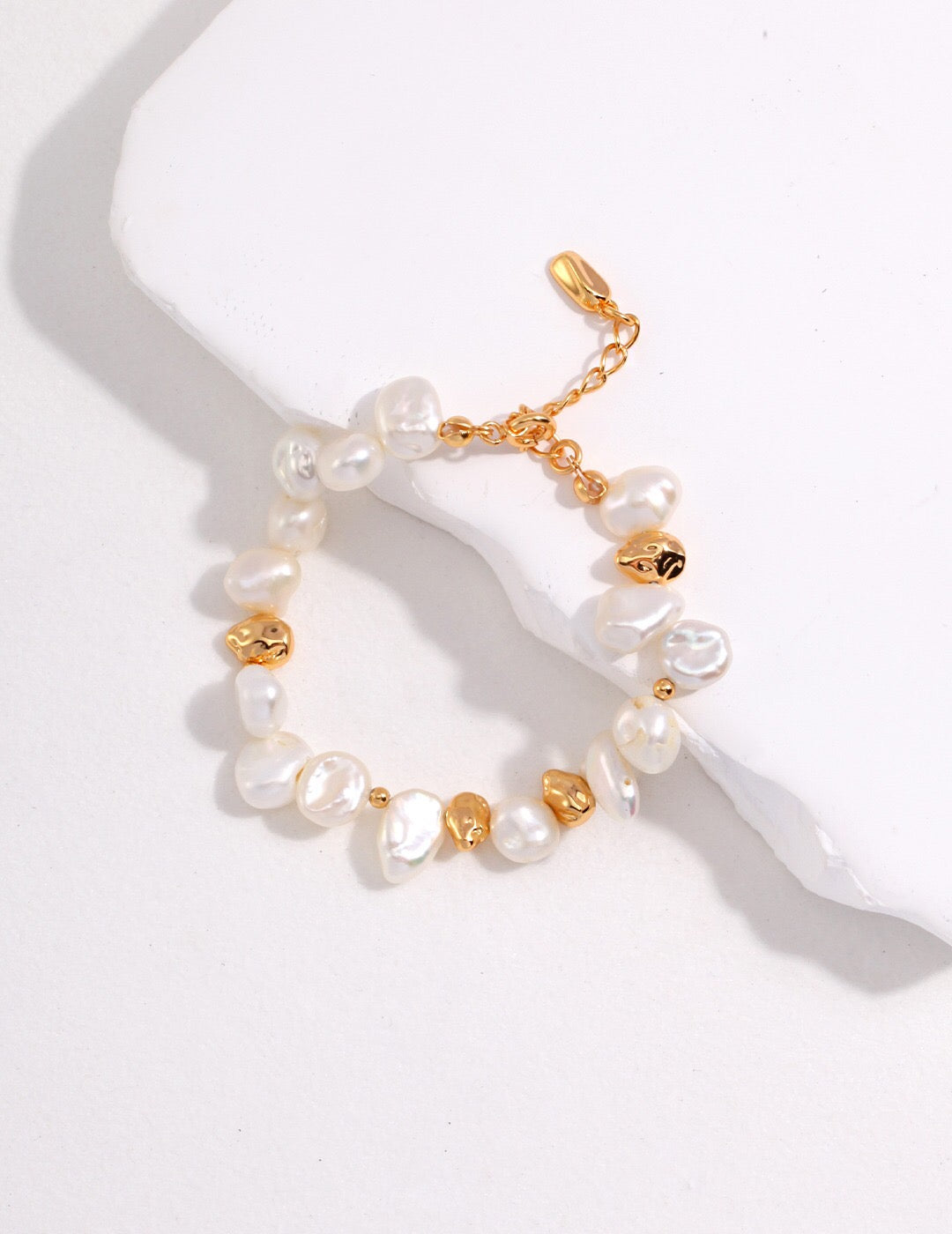 A handcrafted Baroque Pearl Beaded Bracelet featuring natural pearls and gold vermeil, elegantly displayed on a soft surface.