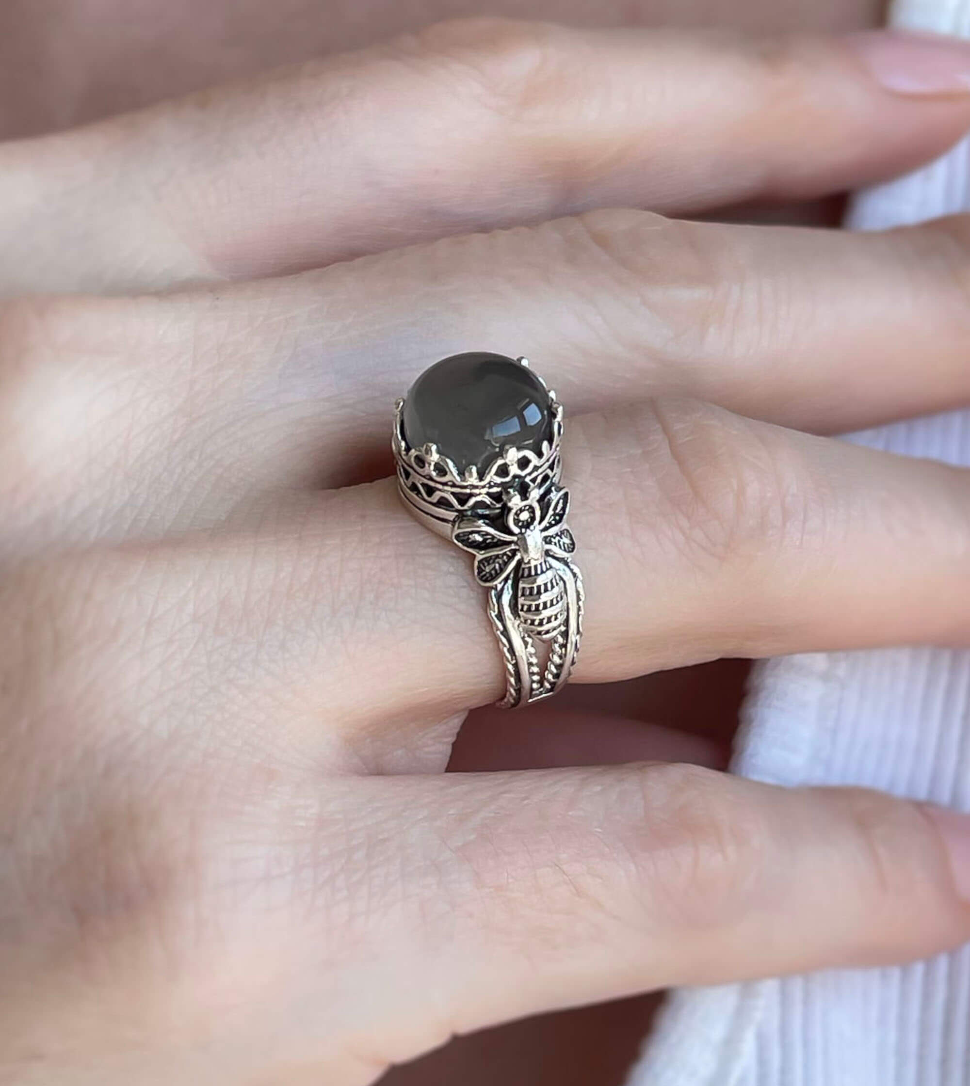 A beautiful sterling silver ring featuring a filigree bee design and a round gray moonstone gemstone, elegantly crafted for women.