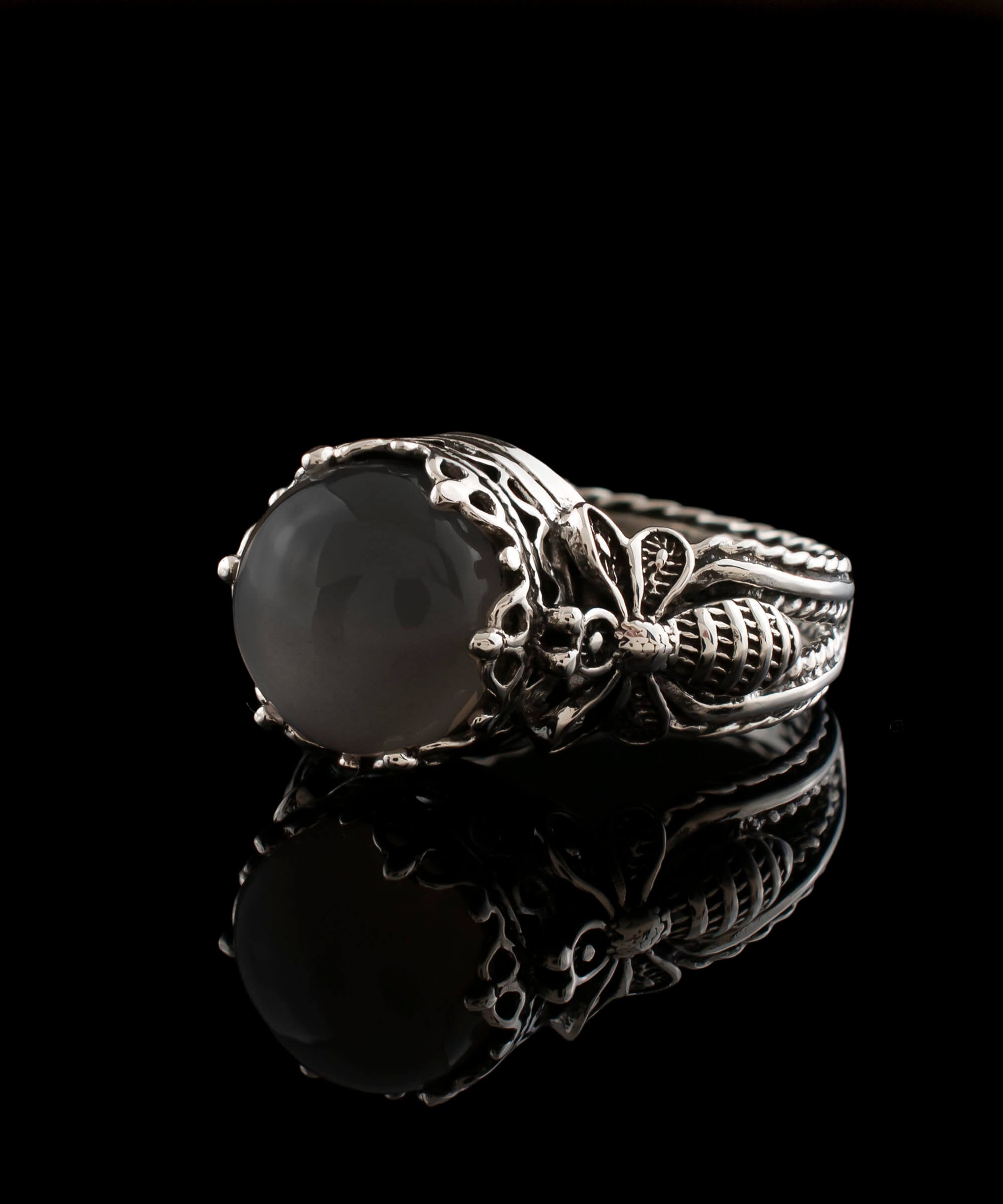 A beautiful sterling silver ring featuring a filigree bee design and a round gray moonstone gemstone, elegantly crafted for women.