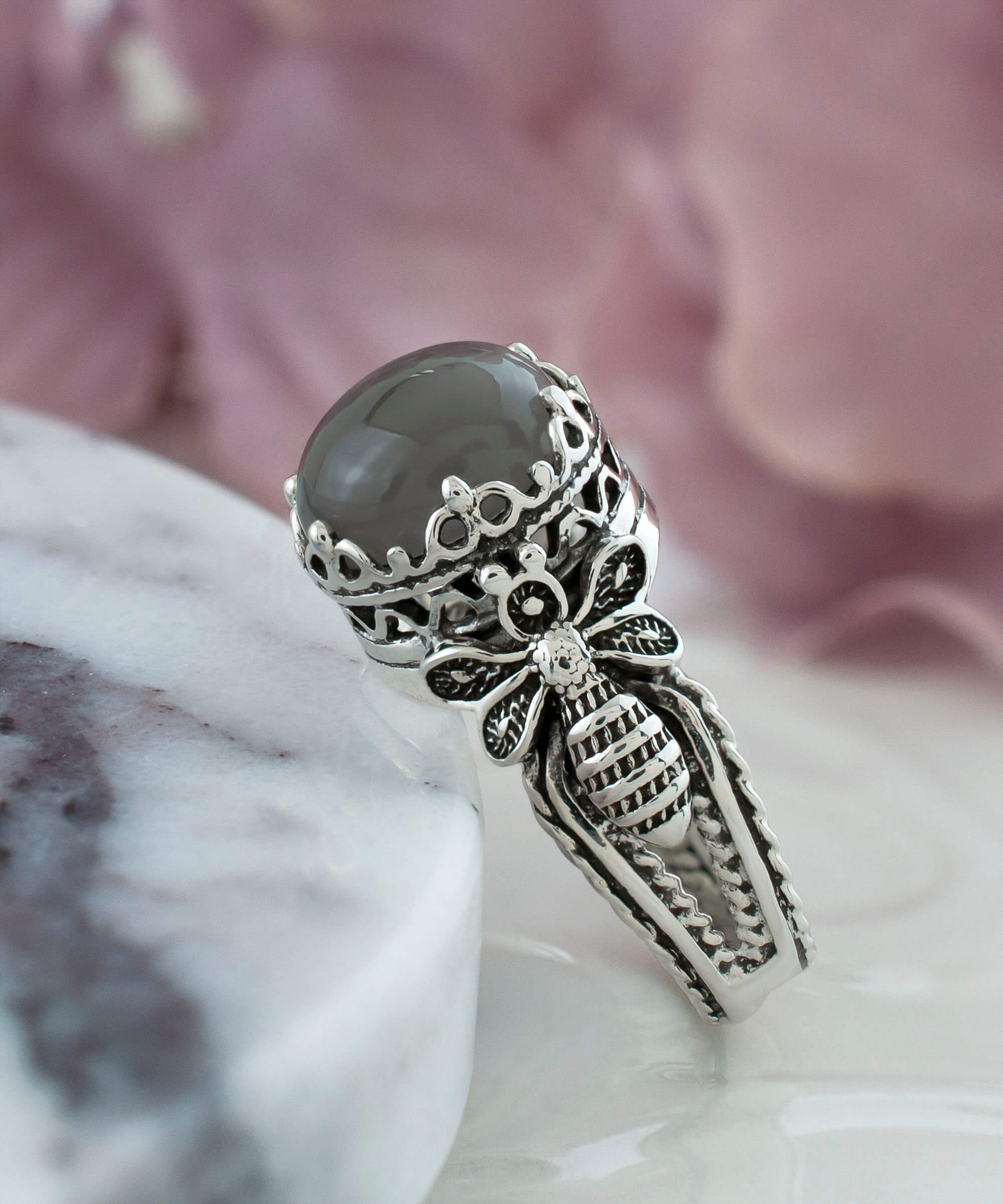 A beautiful sterling silver ring featuring a filigree bee design and a round gray moonstone gemstone, elegantly crafted for women.