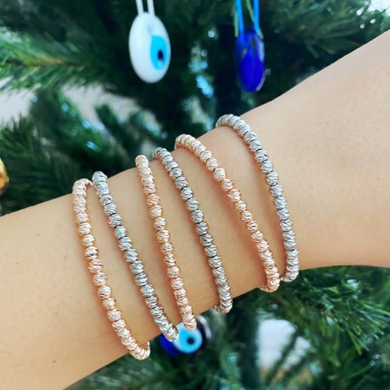 A stylish beaded bangle bracelet in rose gold and silver, showcasing its adjustable cuff design and handmade craftsmanship.