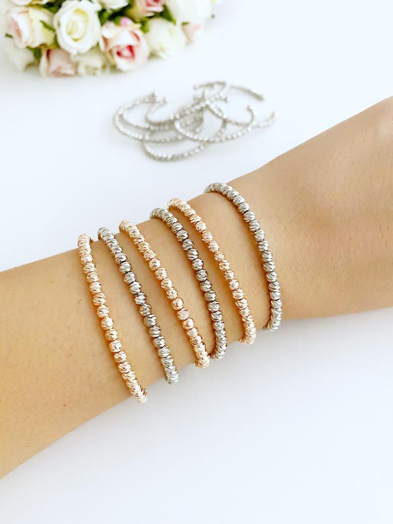 A stylish beaded bangle bracelet in rose gold and silver, showcasing its adjustable cuff design and handmade craftsmanship.