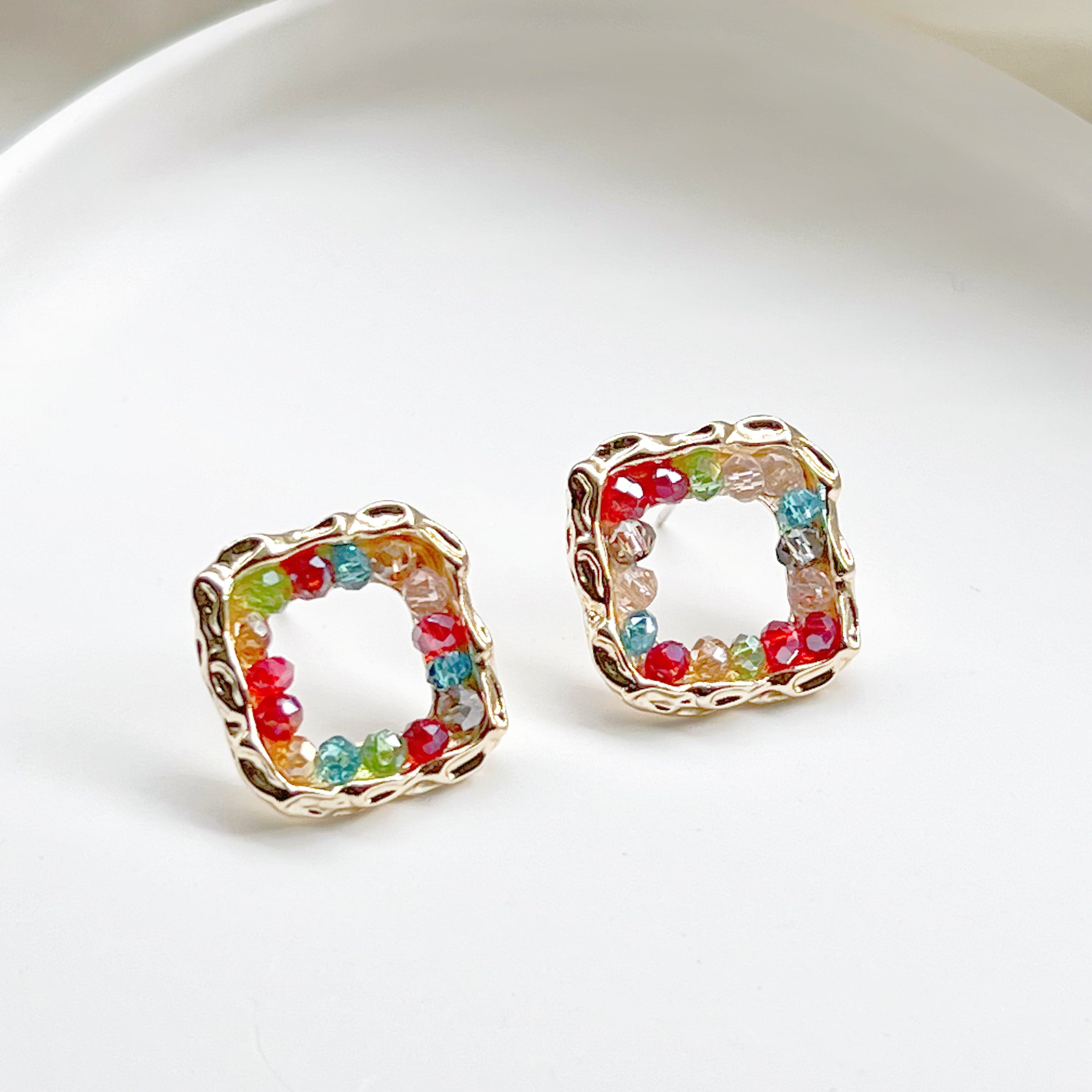 A pair of handmade rainbow beads on square hoop earrings, featuring colorful beads set in a gold-plated square base.