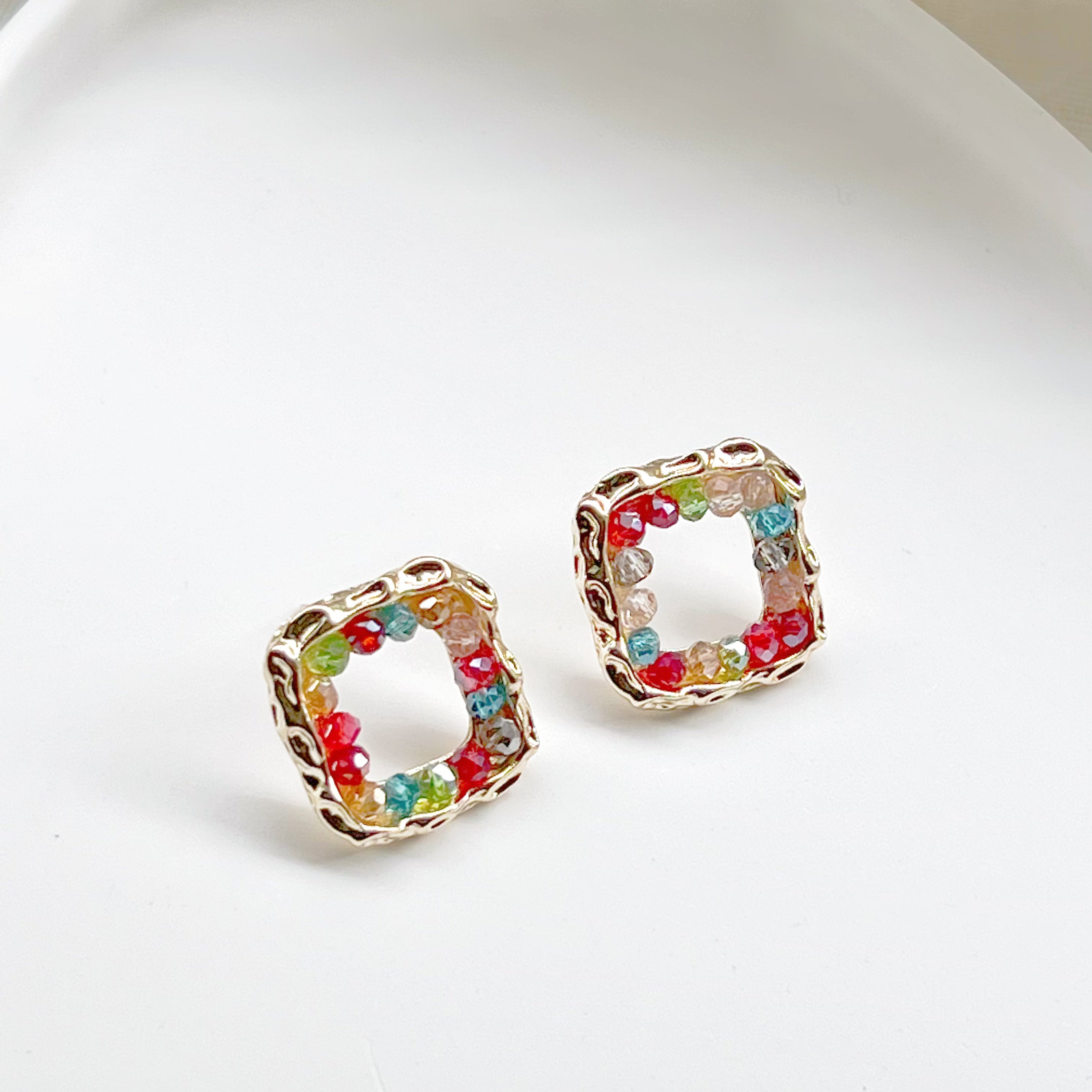 A pair of handmade rainbow beads on square hoop earrings, featuring colorful beads set in a gold-plated square base.