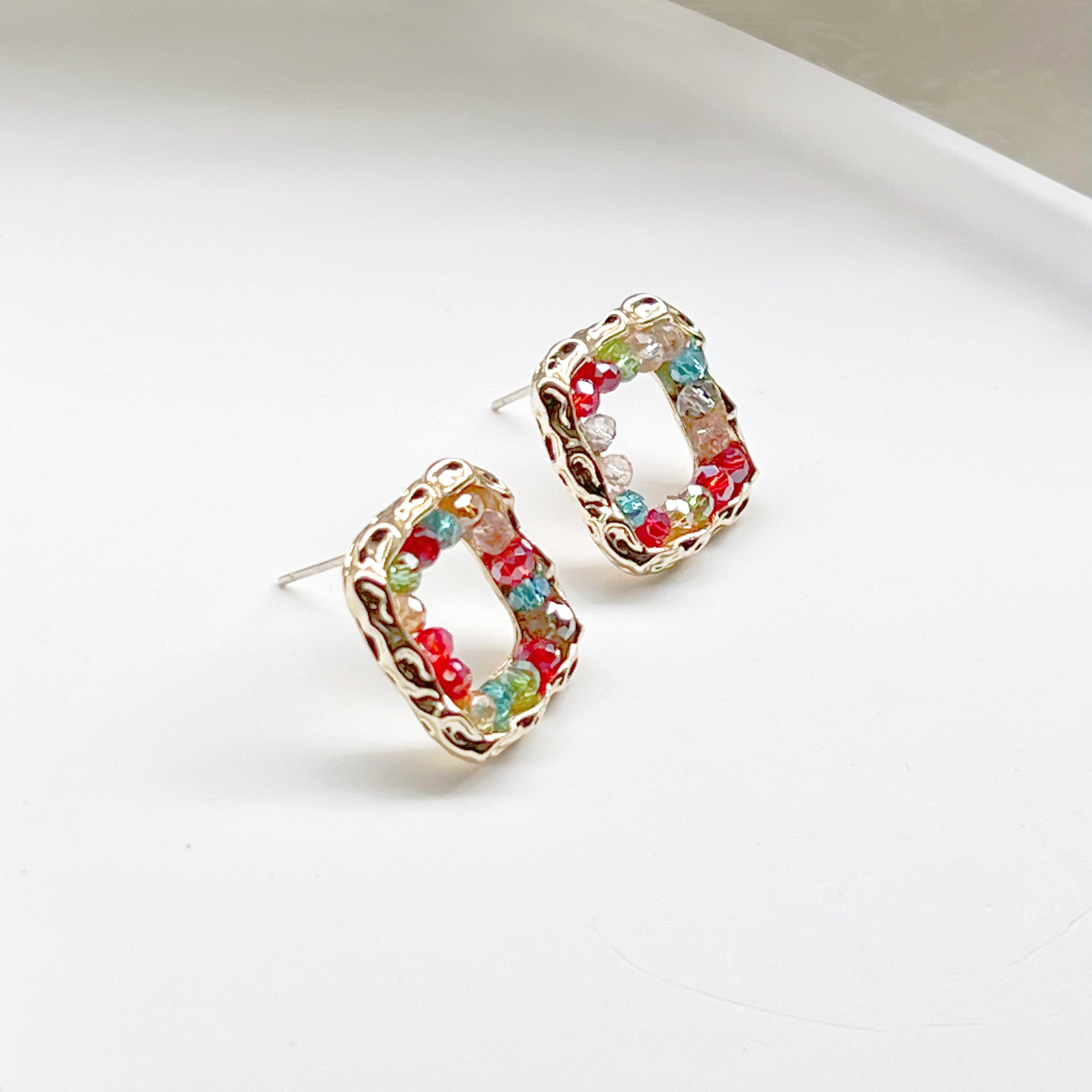 A pair of handmade rainbow beads on square hoop earrings, featuring colorful beads set in a gold-plated square base.