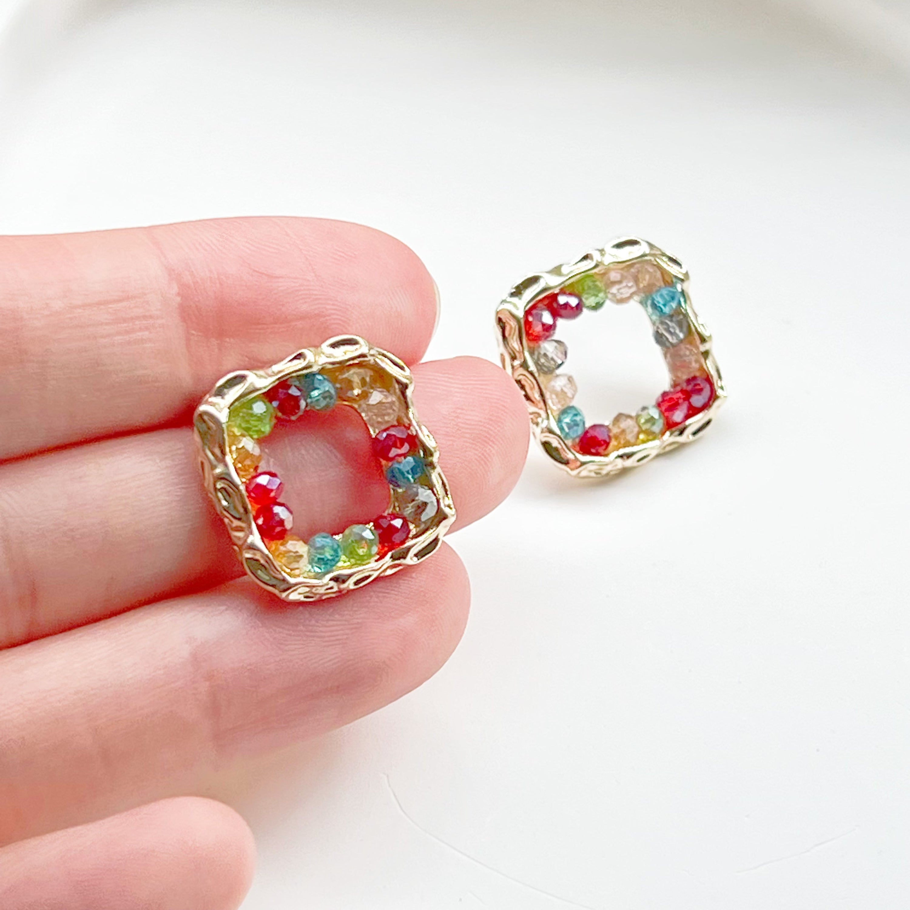 A pair of handmade rainbow beads on square hoop earrings, featuring colorful beads set in a gold-plated square base.