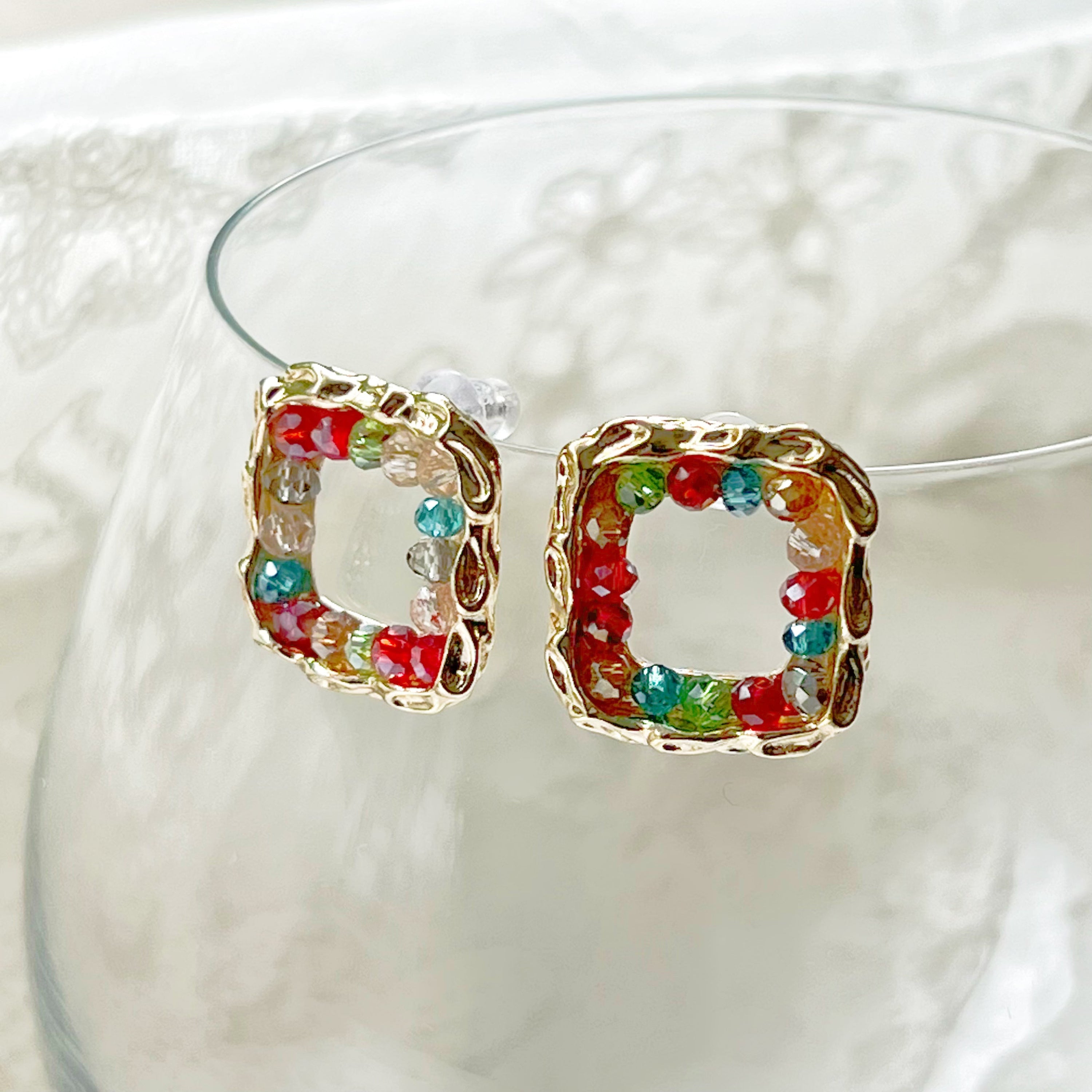 A pair of handmade rainbow beads on square hoop earrings, featuring colorful beads set in a gold-plated square base.